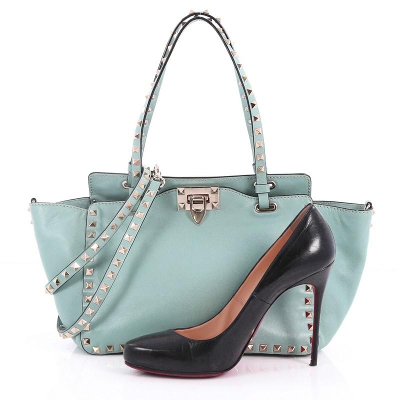 This authentic Valentino Rockstud Tote Soft Leather Small mixes edgy style with luxurious detailing. Crafted from seafoam green soft leather, this stylish tote features dual tall flat handles, gold-tone pyramid stud trim details, signature clasp
