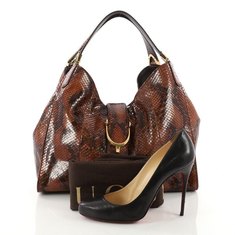 This authentic Gucci Soft Stirrup Tote Python Medium in luxurious and sleek design is made for all seasons. Crafted from genuine brown python skin, this exotic hobo-style shoulder bag features side to side looped dual-flat handles with unique spur