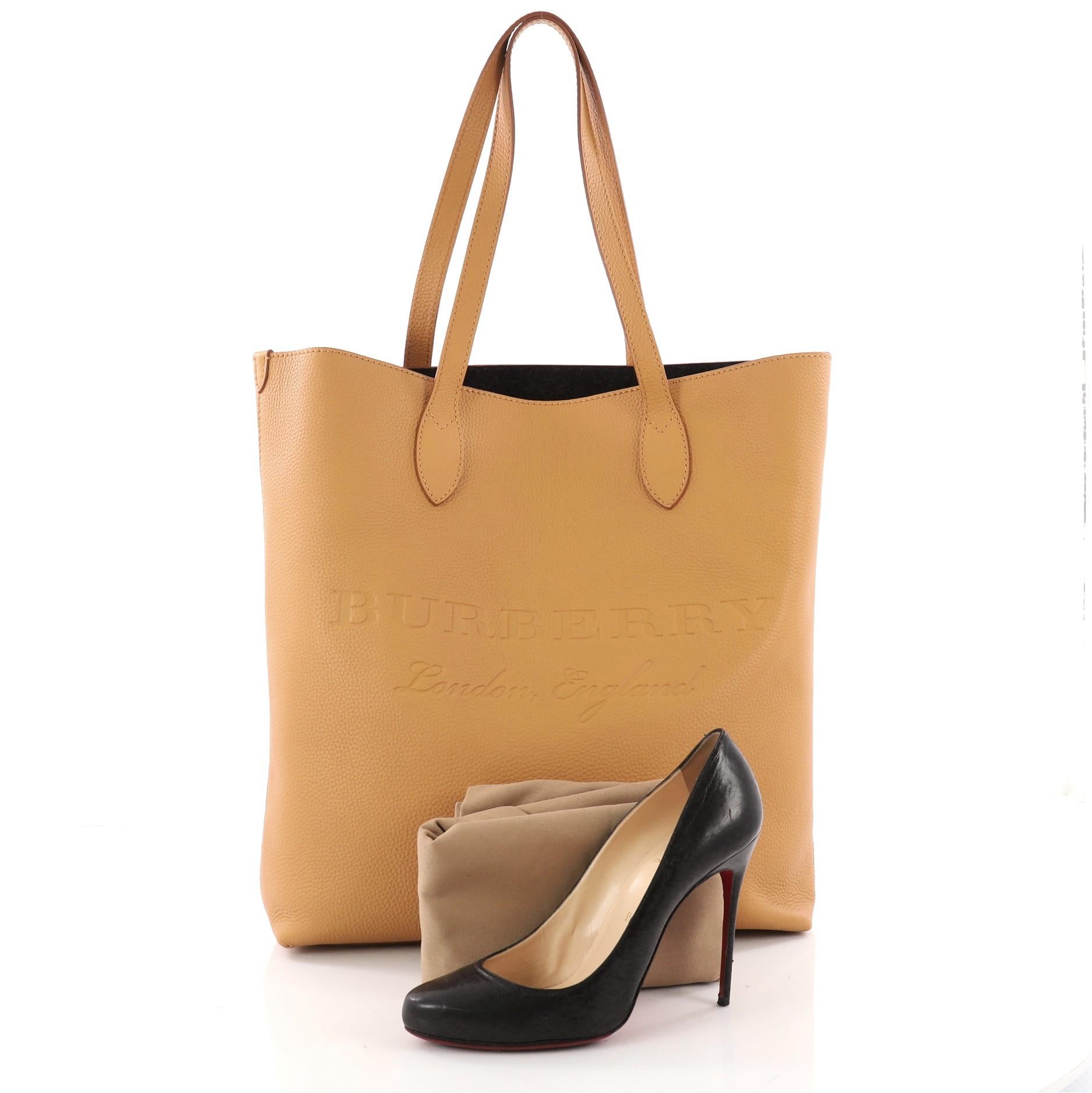 This authentic Burberry Remington Tote Embossed Leather Tall is a minimalist bag perfect for your daily excursions. Crafted in mustard leather, this chic bag features dual-flat leather handles, embossed logo at center front, and gold-tone hardware