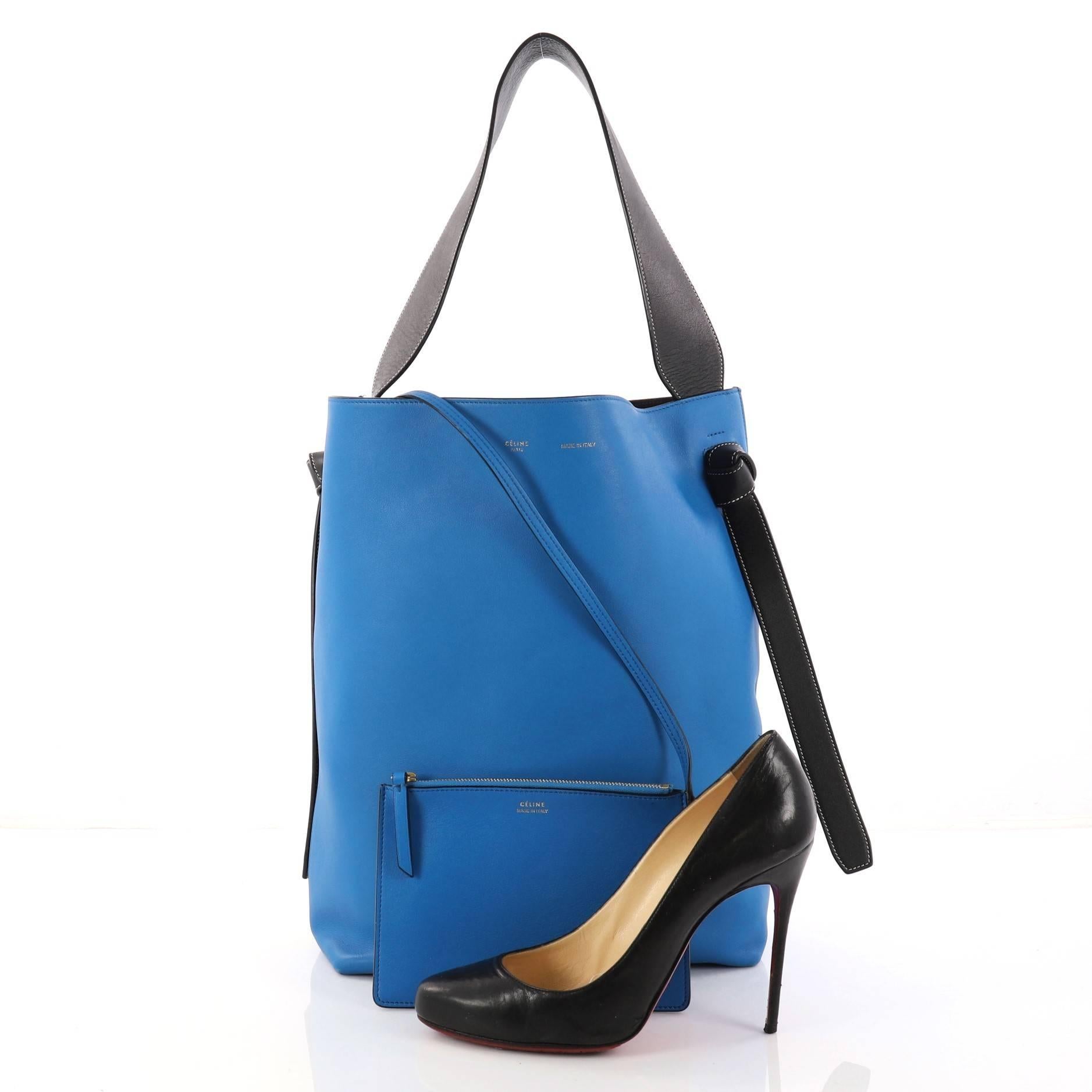 This authentic Celine Twisted Cabas Tote Calfskin Small is a youthful accessory made for everyday excursions. Crafted from blue and teal calfskin leather, this fresh tote features black leather looping shoulder strap with knot ends, stamped logo at