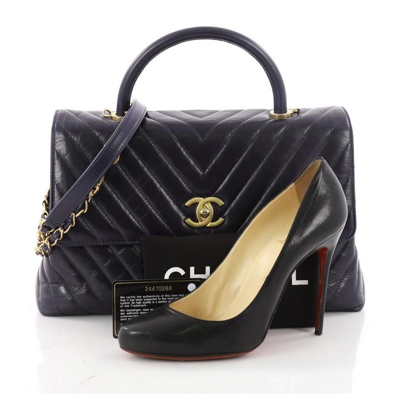 This authentic Chanel Coco Top Handle Bag Chevron Calfskin Large mixes youthful elegance with a timeless flair. Crafted in chevron quilted navy aged calfskin, this bag features single loop leather handle, detachable leather strap, and aged gold-tone