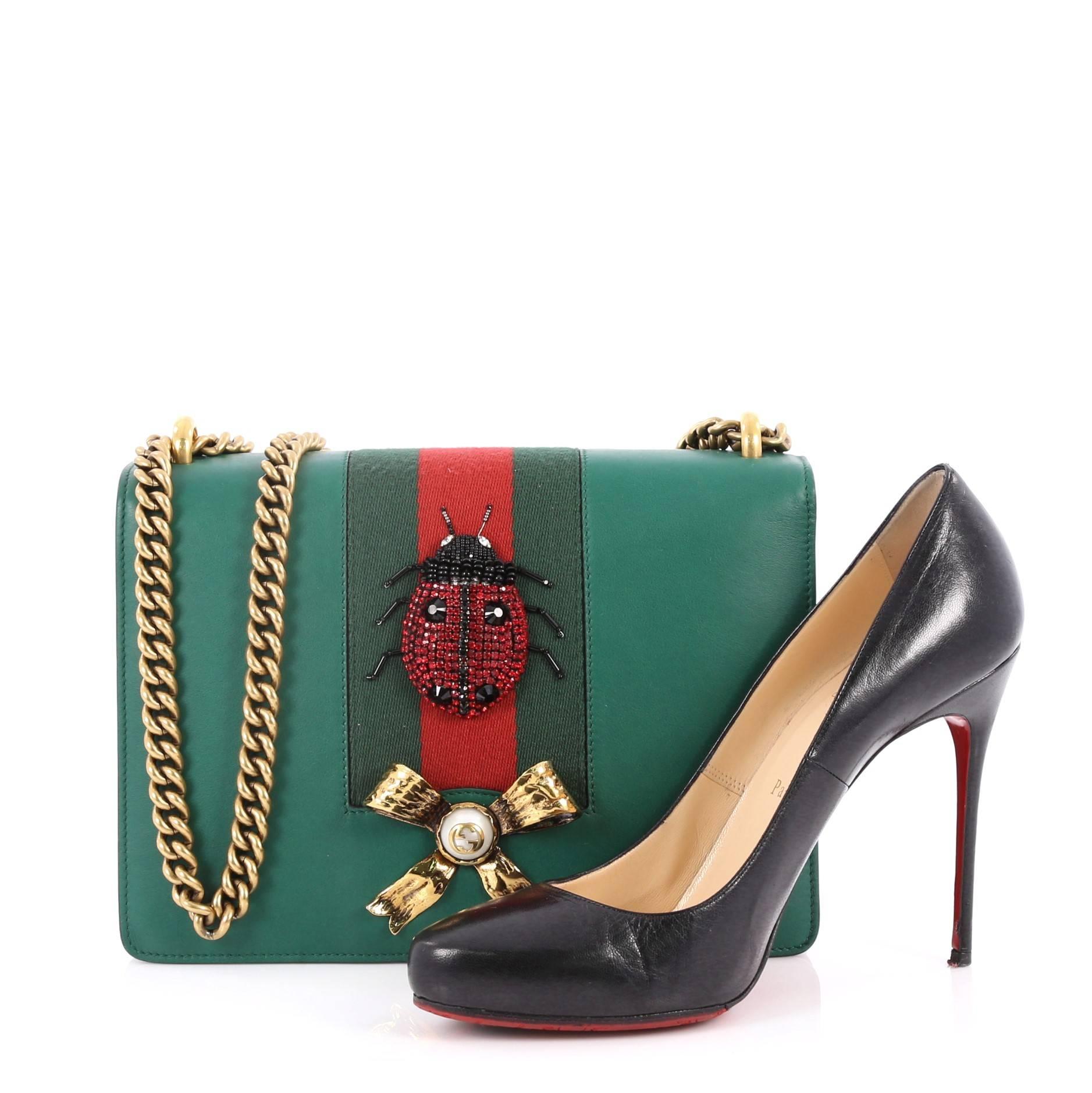 This authentic Gucci Web Peony Chain Shoulder Bag Embellished Leather Medium is the hero piece of your new-season wardrobe. Crafted in green leather embellished with beaded ladybug appliqu̩e and golden metal bow with faux pearl, this stylish bag