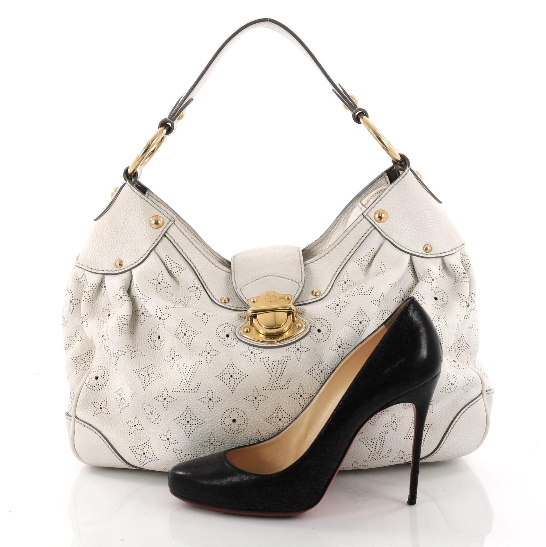 This authentic Louis Vuitton Solar Handbag Mahina Leather PM is an easy, feminine design. Constructed with intricate white perforated monogram mahina leather, this roomy hobo features a reinforced looping leather shoulder strap with gold links,