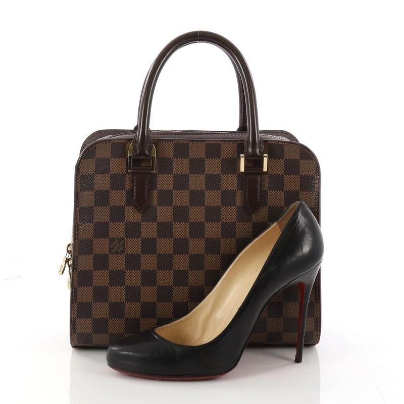 This authentic Louis Vuitton Triana Bag Damier is perfect with any casual outfit. Crafted in damier ebene coated canvas, this bag features dark brown leather rolled handles accented with gold-tone hardware accents. Its zip around closure opens to a