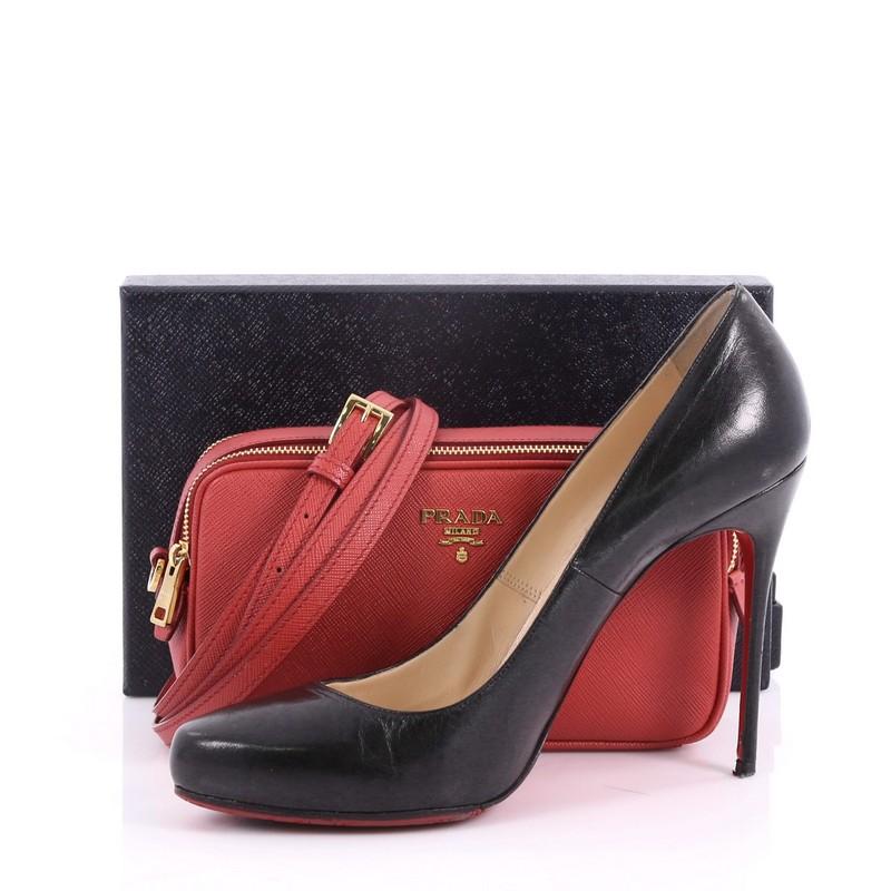 This Prada Double Zip Crossbody Bag Saffiano Leather Mini, crafted in red saffiano leather, features an adjustable leather strap, Prada logo, and gold-tone hardware. Its double zip closure opens to a red fabric interior with multiple card slots.