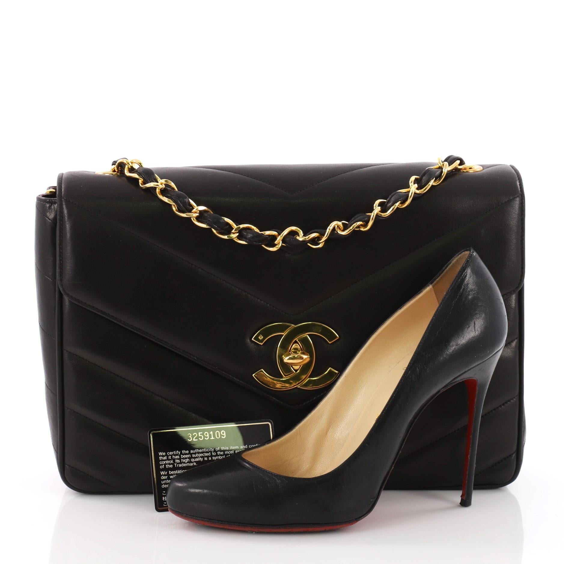 This Chanel Vintage Envelope Flap Chevron Lambskin Jumbo, crafted in black chevron lambskin, features a woven-in leather chain strap, and gold-tone hardware. Its turn-lock closure opens to a maroon leather interior with zip and slip pockets.