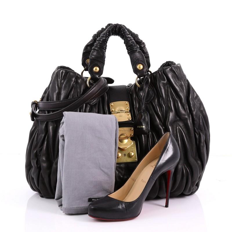 This Miu Miu Coffer Convertible Satchel Matelasse Leather Large, crafted from black matelasse leather, features dual leather top handles, side snap buttons and gold-tone hardware. Its flap tab frontal slide-press closure opens to a black fabric