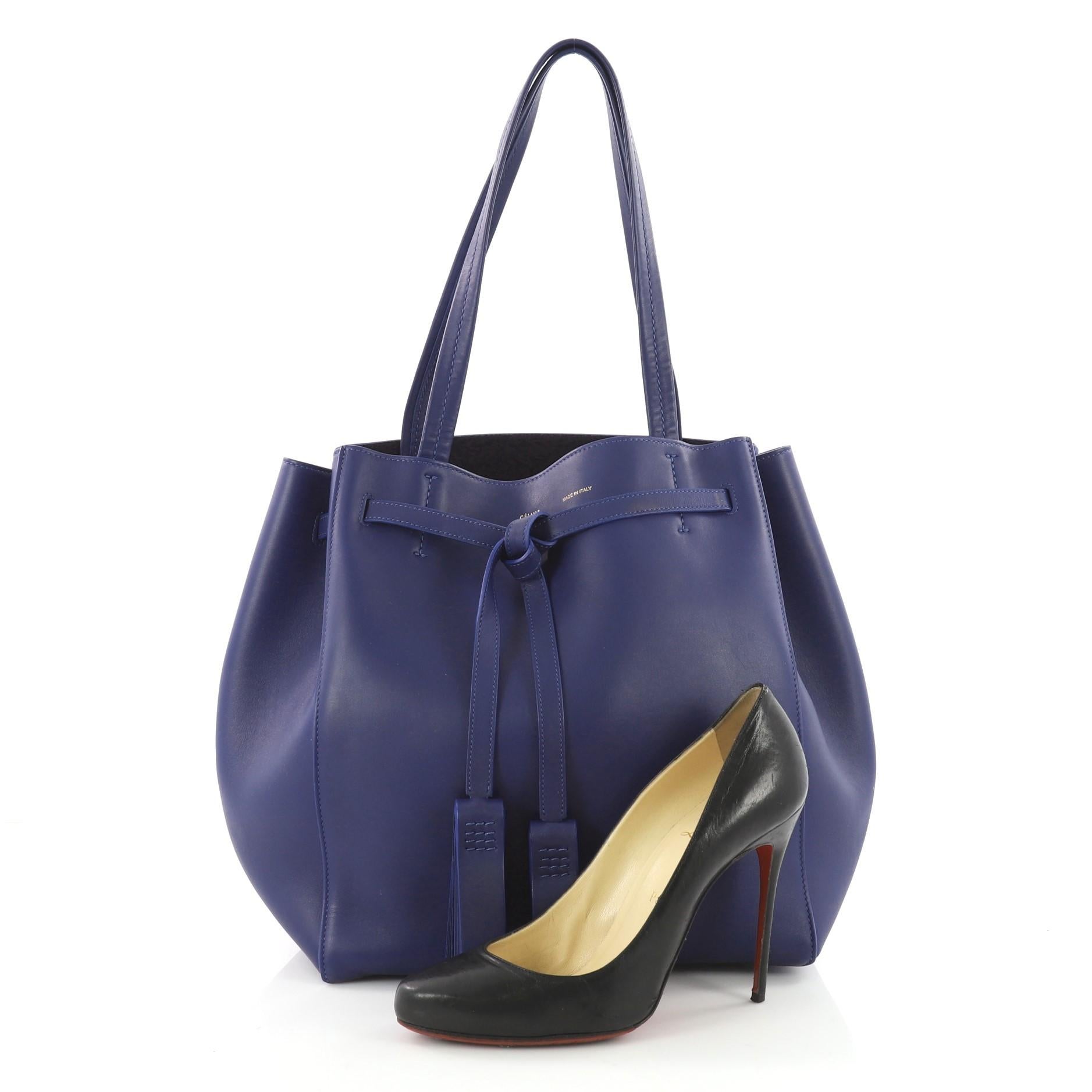 This authentic Celine Phantom Tie Cabas Tassel Tote Leather Small is a fashionista's go-to stylish essential. Crafted from blue leather, this minimalist city tote features dual flat tall handles, stamped Celine logo, and gold-tone hardware accents.
