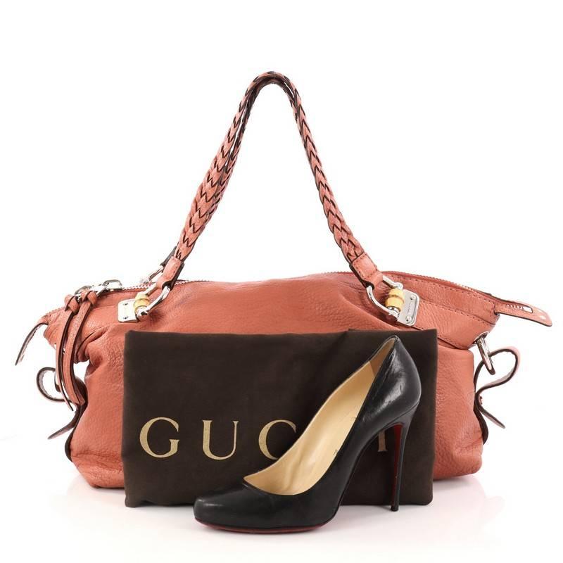 This authentic Gucci Bamboo Bar Shoulder Bag Leather Medium mixes the brand's traditional design with a modern flair. Crafted in dark coral leather, this oversized shoulder bag features dual braided leather handles, adjustable side stripes, bamboo