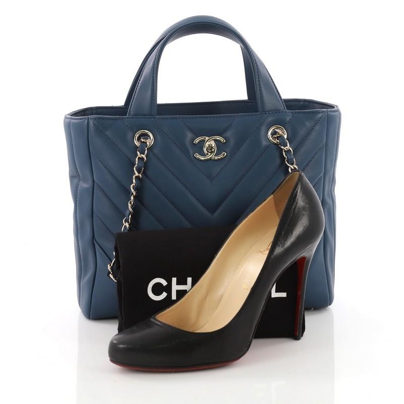 This Chanel Statement Shopping Tote Chevron Calfskin Small, crafted in blue calfskin leather, features dual flat leather handles, woven in leather chain link strap with leather pads and silver-tone hardware. Its CC turn-lock closure opens to a blue