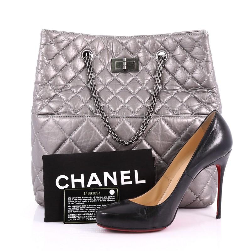 This Chanel Reissue Tote Quilted Aged Calfskin Tall, crafted from silver quilted aged calfskin, features reissue chain straps, diamond quilted design, and aged silver-tone hardware. Its magnetic snap closure opens to an off-white fabric interior