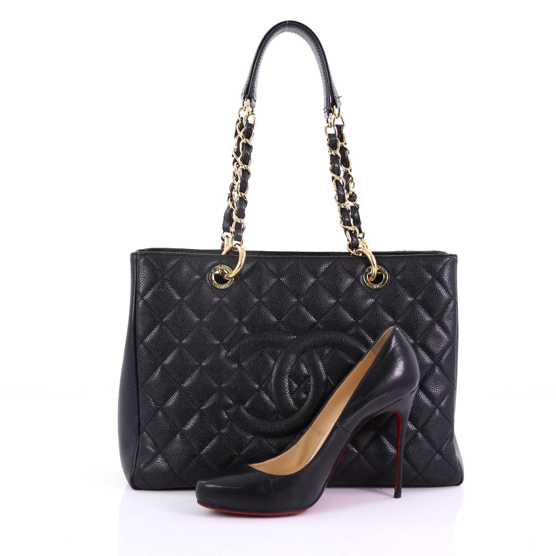This Chanel Grand Shopping Tote Quilted Caviar, crafted in black quilted caviar leather, features woven-in leather chain straps with leather pads, exterior back pocket, and gold-tone hardware. It opens to a black satin interior with two open