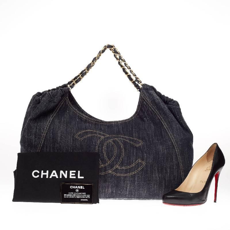 This authentic Chanel Coco Cabas Denim Large is finely crafted in dark blue denim perfect for casual wear. This roomy hobo features an oversized stitched Chanel CC frontal logo, ruching detail and woven-in denim gold chain straps. Its magnetic snap
