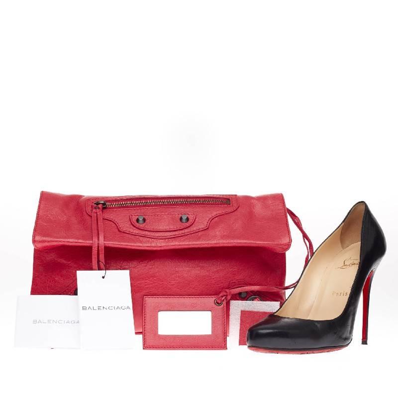 This authentic Balenciaga Envelope Clutch Classic Studs Leather showcases an elegant yet edgy style perfect for day-to-evening looks. Constructed in distressed Rose Thulian red leather, this casual yet chic fold-over flap clutch features a front zip