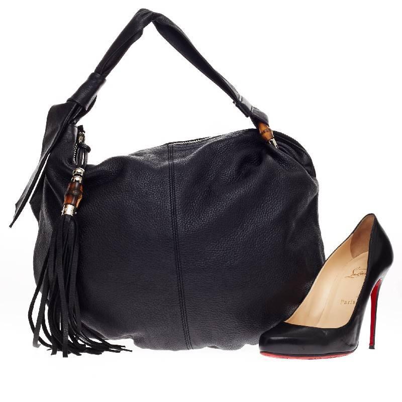 This authentic Gucci Jungle Hobo Leather Medium is made for your everyday casual look. Crafted in black leather, this hobo features wide shoulder straps with signature Gucci bamboo ring details, fringe tassels, and silver-tone hardware accents. Its