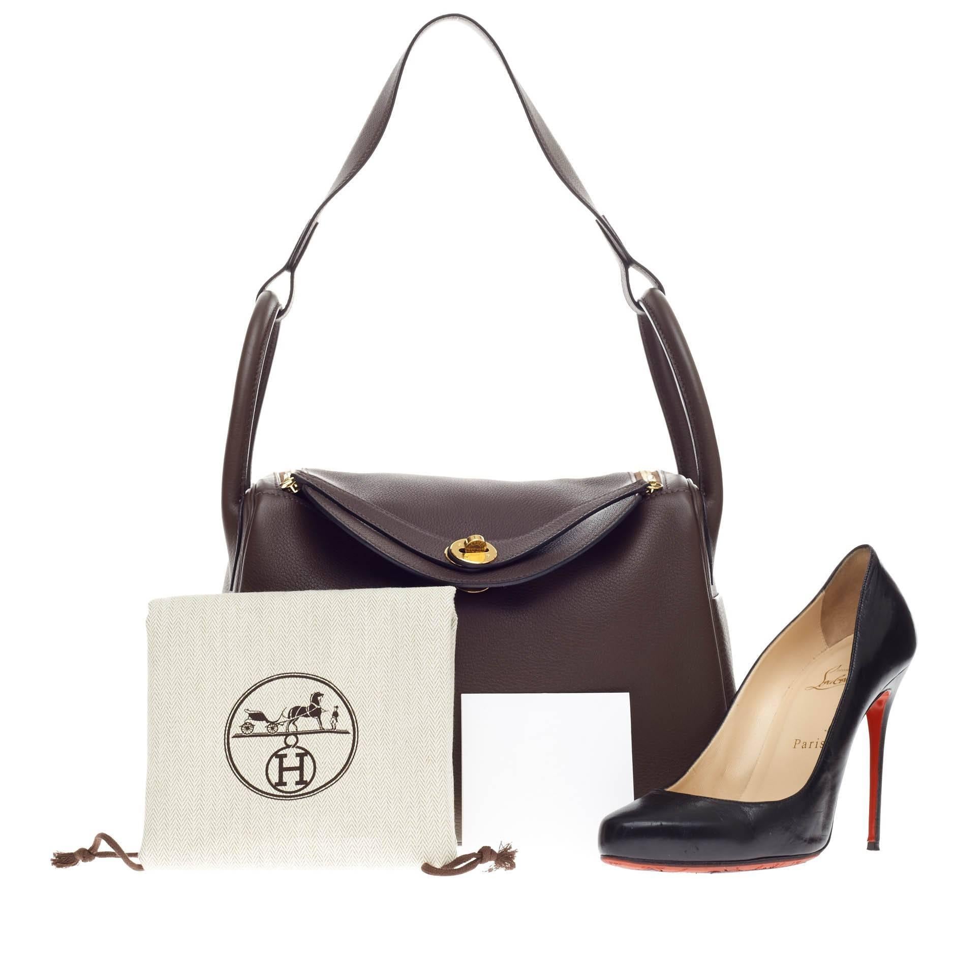This authentic Hermes Lindy Clemence 30 in beautiful, rich Cafe brown clemence is the perfect understated accessory for the modern woman. Accented in polished gold hardware,  this no-fuss shoulder bag features dual rolled handles, two sides slip