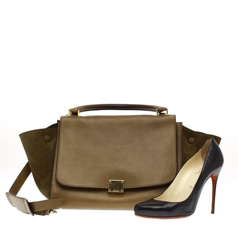 This authentic Celine Suede Trapeze in size Medium is a fashionista's dream. This beautiful bag is constructed with brown leather and matching suede on the wings. It is accented with gold hardware and a full frontal flap with a square press lock