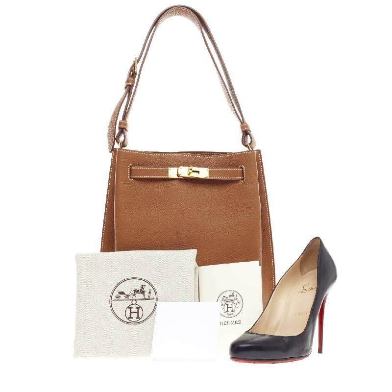 This authentic Hermes So Kelly Togo 22 first released in 2008 is an updated and modern reinterpretation of the Kelly Sport taking its distinct look to Hermes' classic kelly design. Crafted in gold togo leather, this luxurious hobo-inspired bag