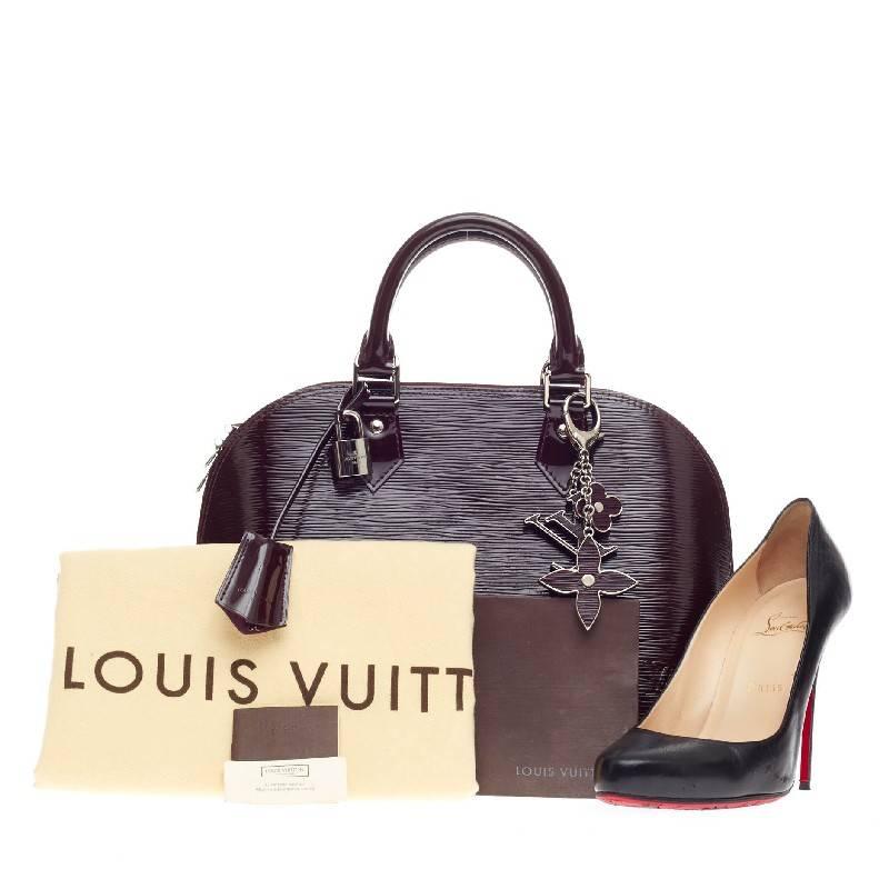 This authentic Louis Vuitton Alma Electric Epi Leather PM in prune is elegant and as classic as they come. Constructed with Louis Vuitton's signature sturdy electric epi leather in a dome-like silhouette, this iconic bag features dual rolled