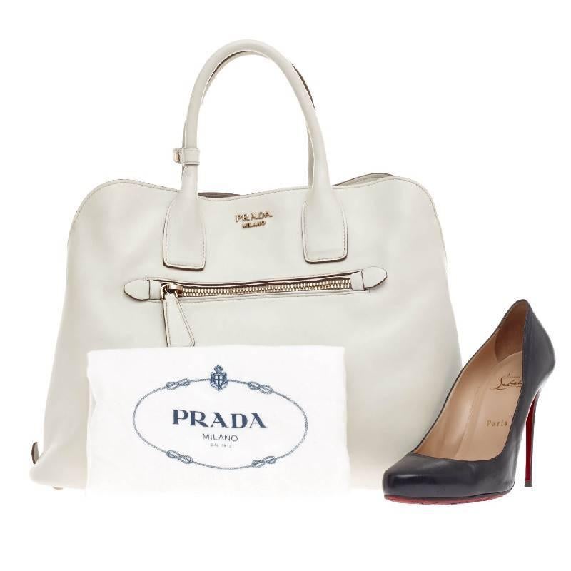 This authentic Prada Cuir Open Promenade Tote Calfskin Leather is elegant in its simplicity and structure. Crafted in off-white smooth calfskin leather, this sleek tote features dual-rolled handles, four base studs, front zip pocket, gold-tone