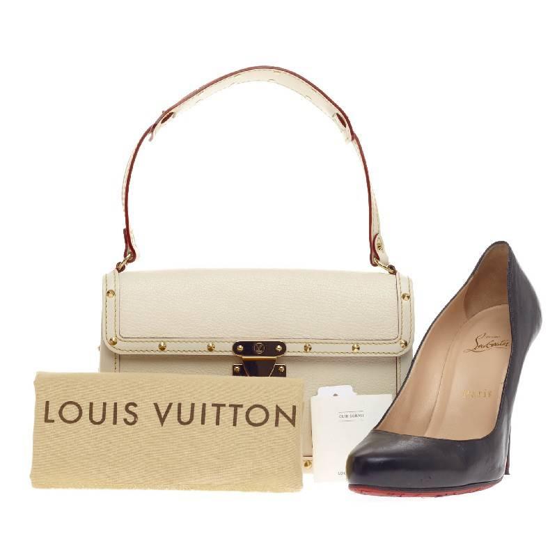 This authentic Louis Vuitton Suhali L'Aimable Leather showcases a structured yet eye-catching elegant design. Crafted from sturdy white goatskin leather, this boxy flap features polished gold-tone hardware that includes corner plates and decorative