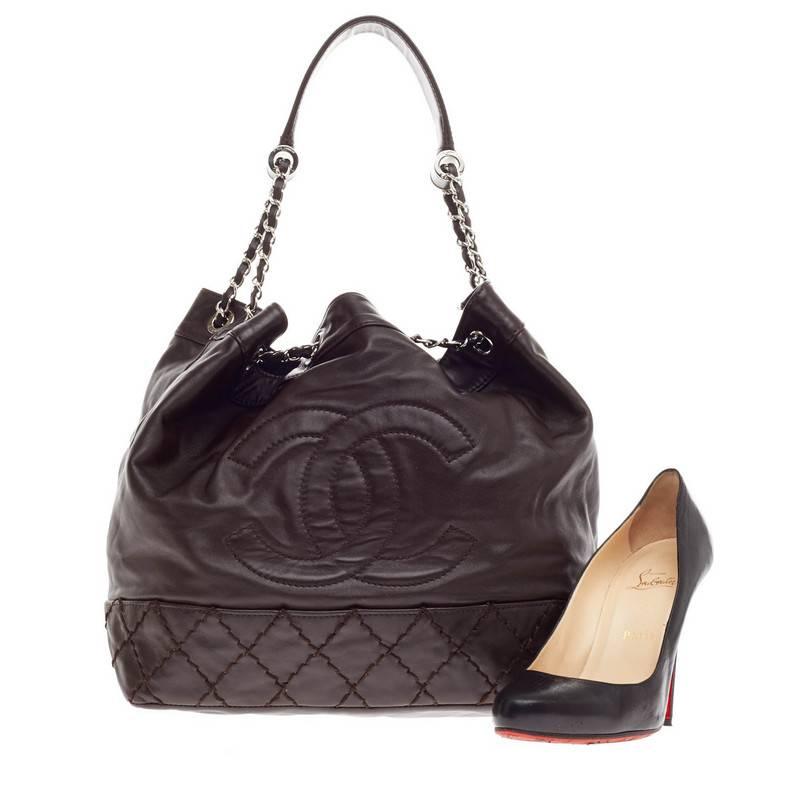 This authentic Chanel CC Drawstring Bucket Bag Lambskin in rich, dark brown exudes a nature of casual elegance. Crafted in lambskin leather with signature diamond quilting details, this chic bucket-style bag features Chanel's oversized stitched CC