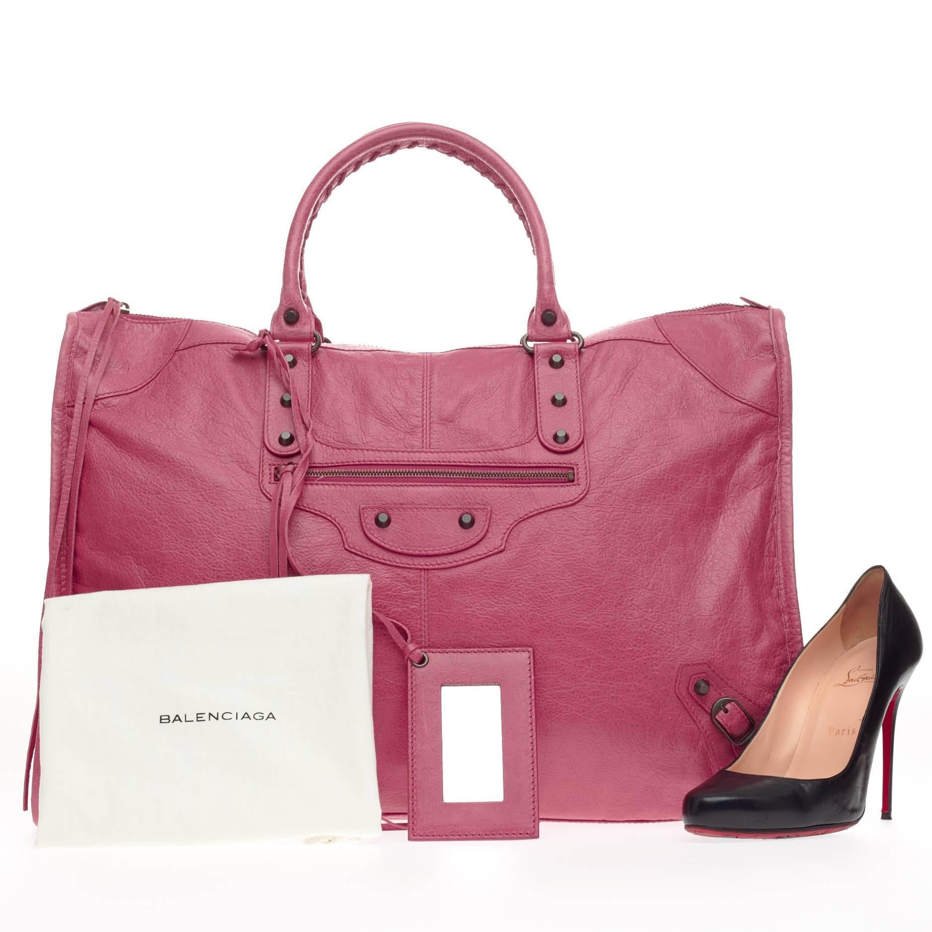 This authentic Balenciaga Weekender Classic Studs Leather is a stylish and fun accessory made for light travels and weekend getaways. Constructed from beautiful cyclamen pink leather, this oversized, lightweight carryall features braided woven