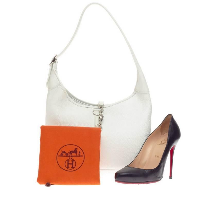 This authentic Hermes Trim Clemence 31 is a luxurious and stylish shoulder bag crafted in elegant white clemence leather. An iconic, discontinued bag, the classic Trim bag features a flat silhouette, looped shoulder strap and a top flap polished