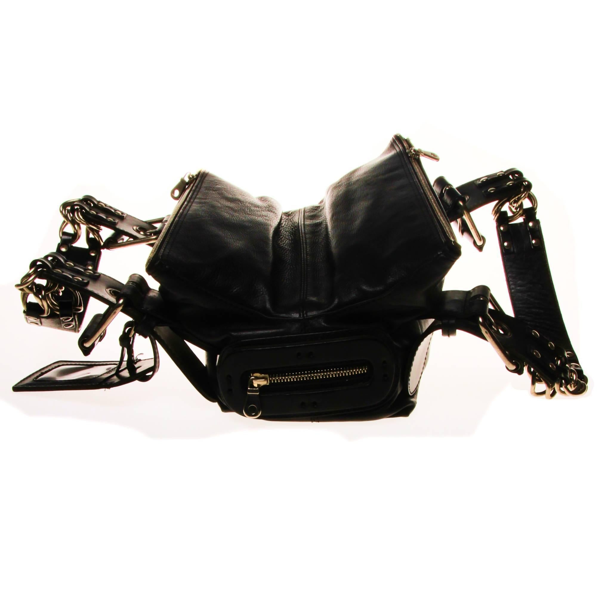 This Chloe handbag is composed of black grain leather and features double top handles with buckle and chain features. There are two exterior top zipper compartments and one interior zipper compartment. Branded zipper compartment on the back