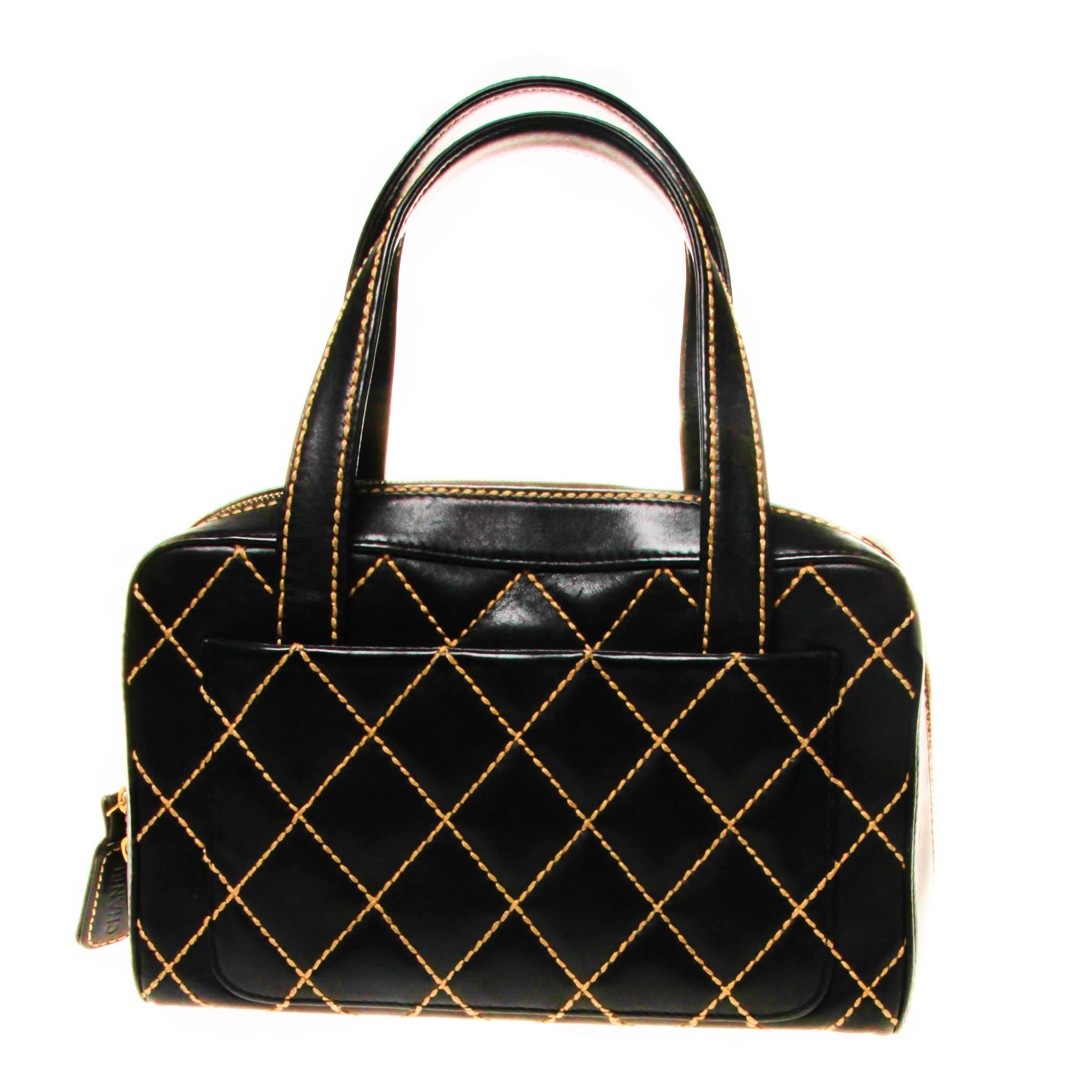 This bag has a classic, structured bowler shape crafted of luxurious black calfskin leather with a bold white stitched diamond quilt.

It features smooth black leather outer edges, strap top handles and a gold Chanel CC on the front top edge. The