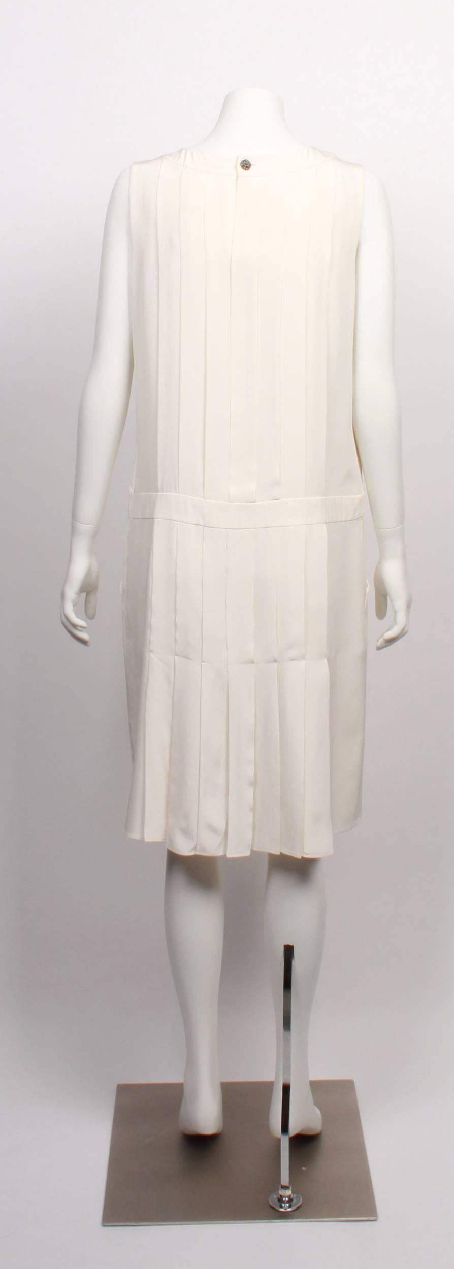  Chanel Silk Flapper Dress in 100% ivory silk. 
Classic yet modern, with knife pleat detail, cutaway pockets and statement Chanel button closure.



 