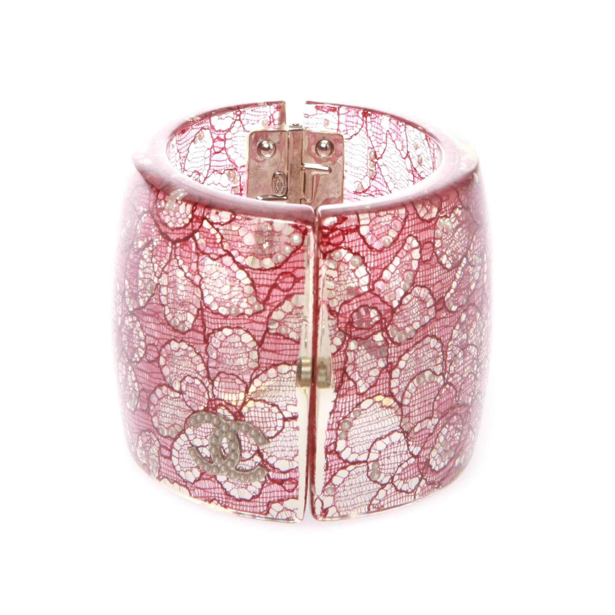 	
A stunning CHANEL Camelia lace and faux pearls embellished clear resin cuff.
It features clear resin and pink lace embellished hinged cuff with faux pearls throughout, and a hinged magnetic clasp closure.
Add this Investment piece to your