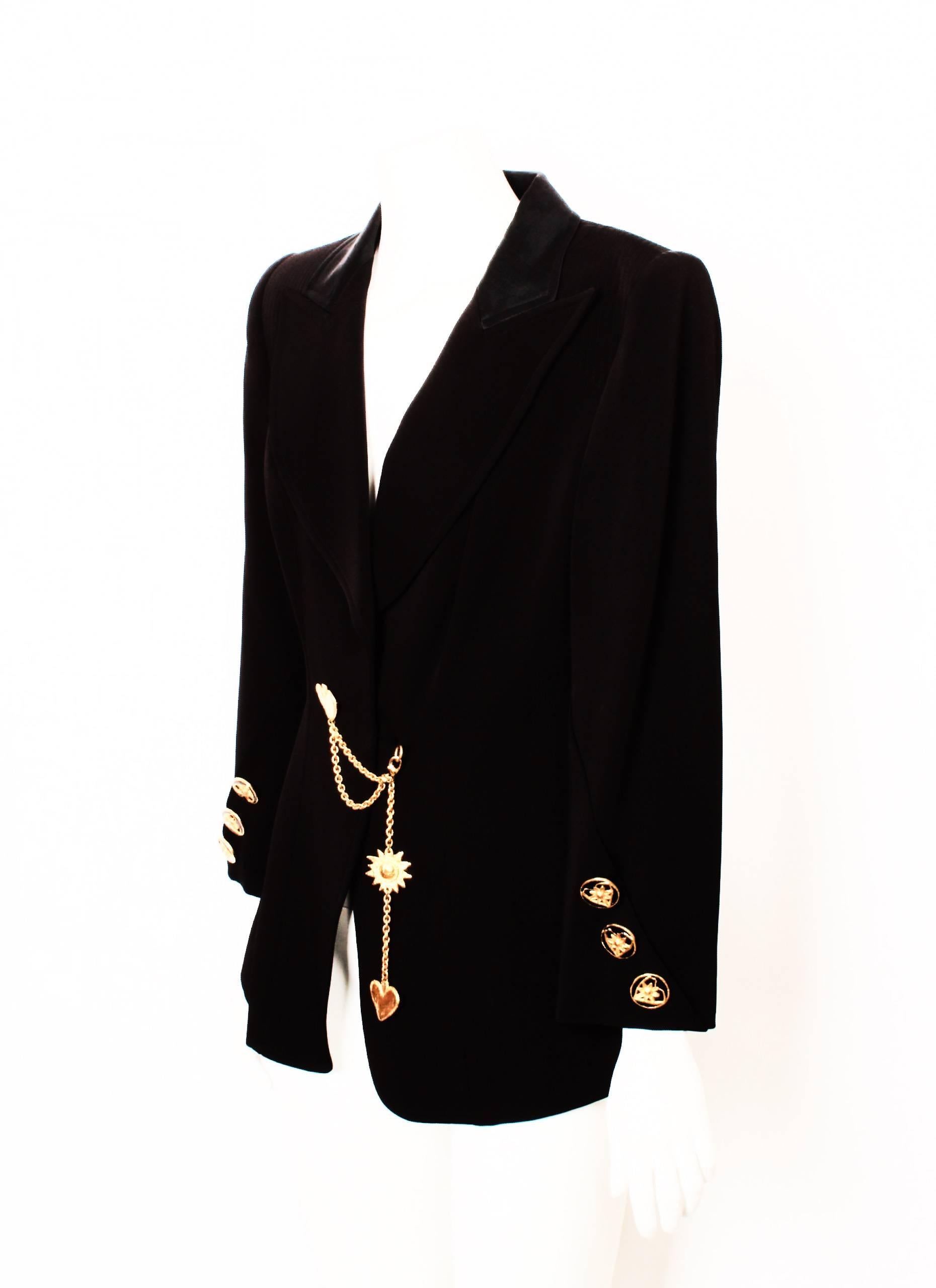 CHRISTIAN LACROIX tailored jacket in black with detachable sun and heart charm chain accessory. Features beautiful ornate gold and black heart and flower buttons, feature pockets and feature top stitching on the shoulder panels.
A magnificent