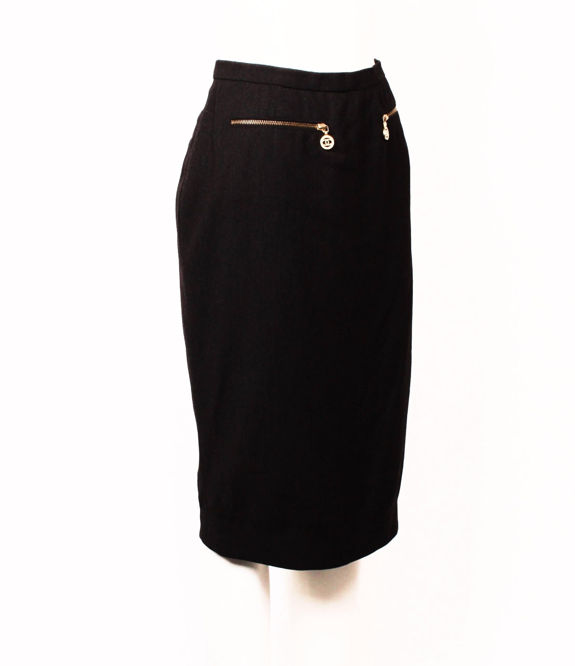 Gorgeous Chanel Boutique fitted pencil skirt in dark charcoal grey.
Features decorative gold zipper pockets with iconic Chanel CC logo pulls.  The skirt is just below knee length and is fully lined. Back invisible zipper and hook and eye