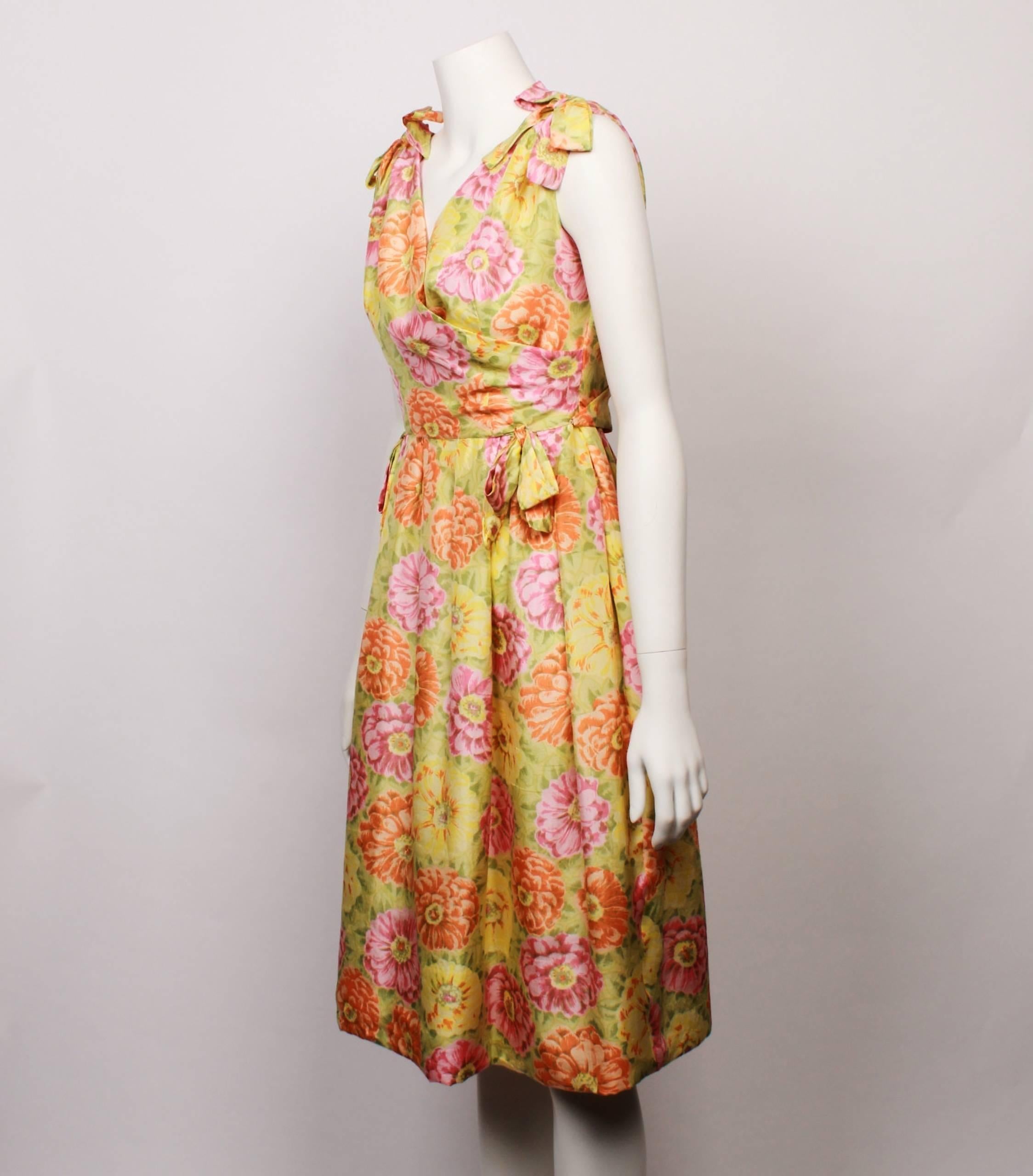 Early 1960s Christian Dior demi– couture new look floral party dress in 100% silk multi coloured floral fabric in hues of fresh citrus green, yellow, orange and pink. Cross over front and back bodice with a slightly gathered skirt. 
Features
