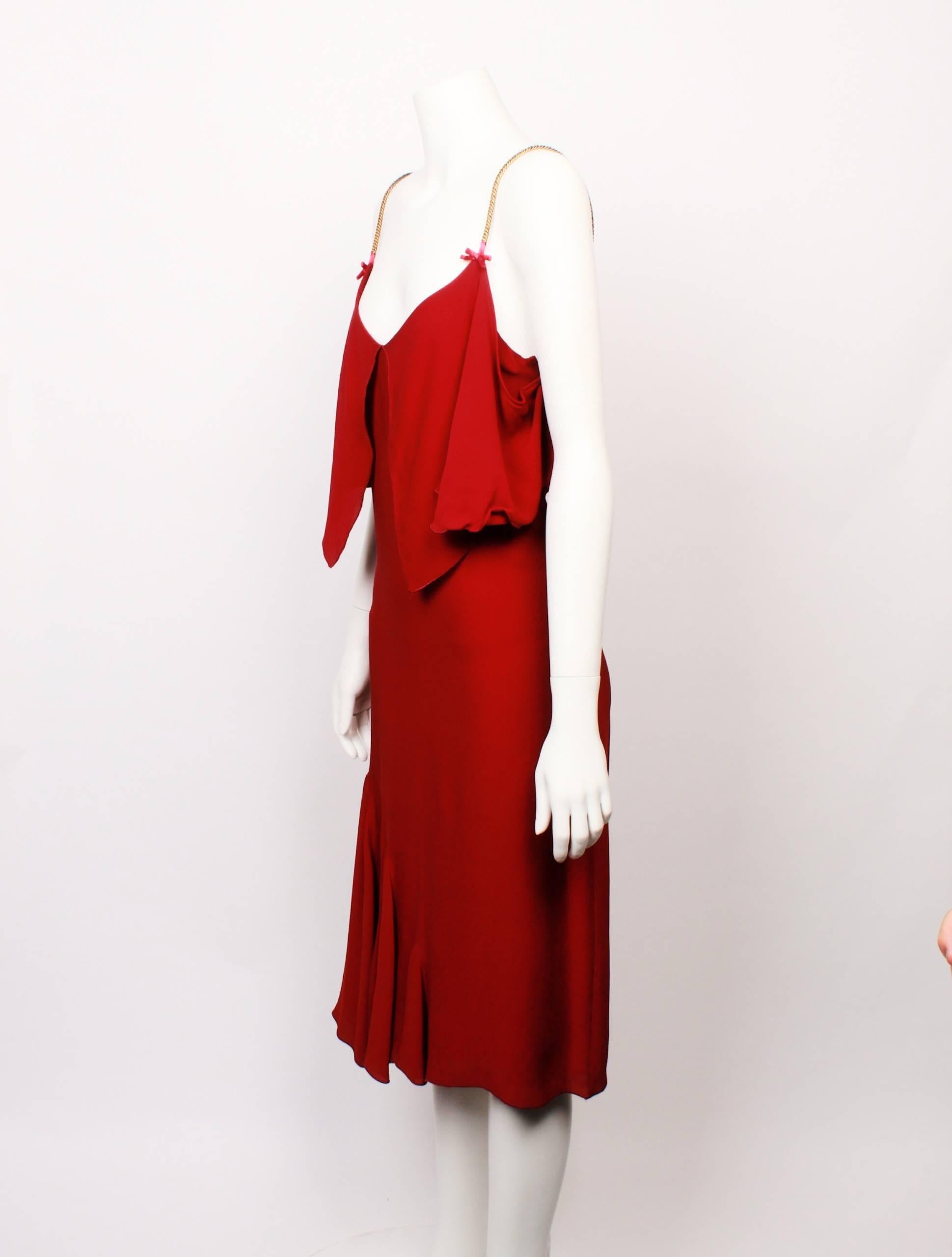 Elegant Viktor & Rolf Red Jersey Cocktail Dress features gold chain straps and cute satin bow detail. 
The silhouette is classic yet sexy with a flared gored panel on one side of the hemline. 
Bodice features gorgeous maxi frill overlay that forms a