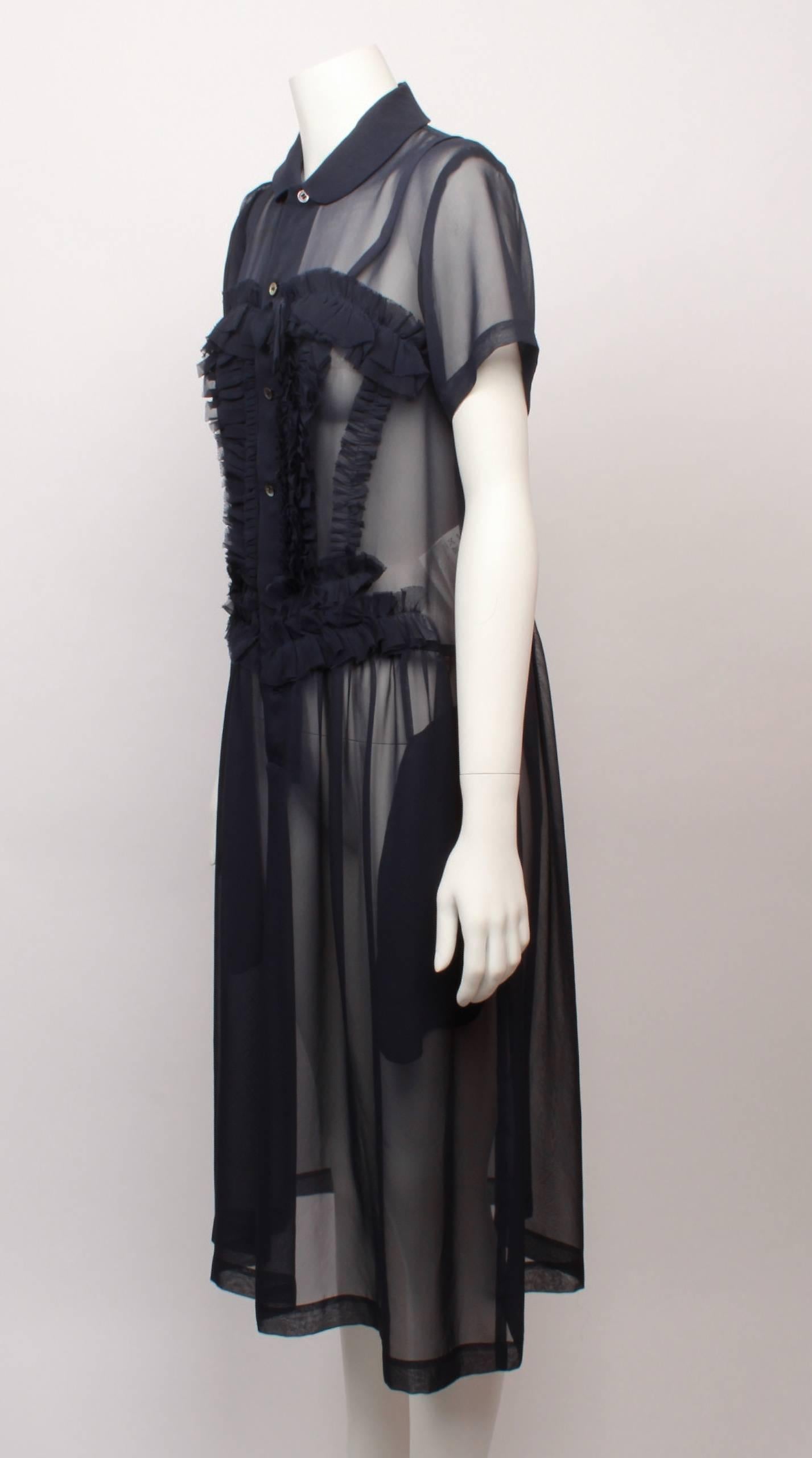 Comme des Garcons Sheer navy silk chiffon frill dress features soft tuxedo frills with decorative bow.  Frills also run horizontally above the bust line to create a cute sweetheart shape. 

Dress has a peter pan collar, button through front placket