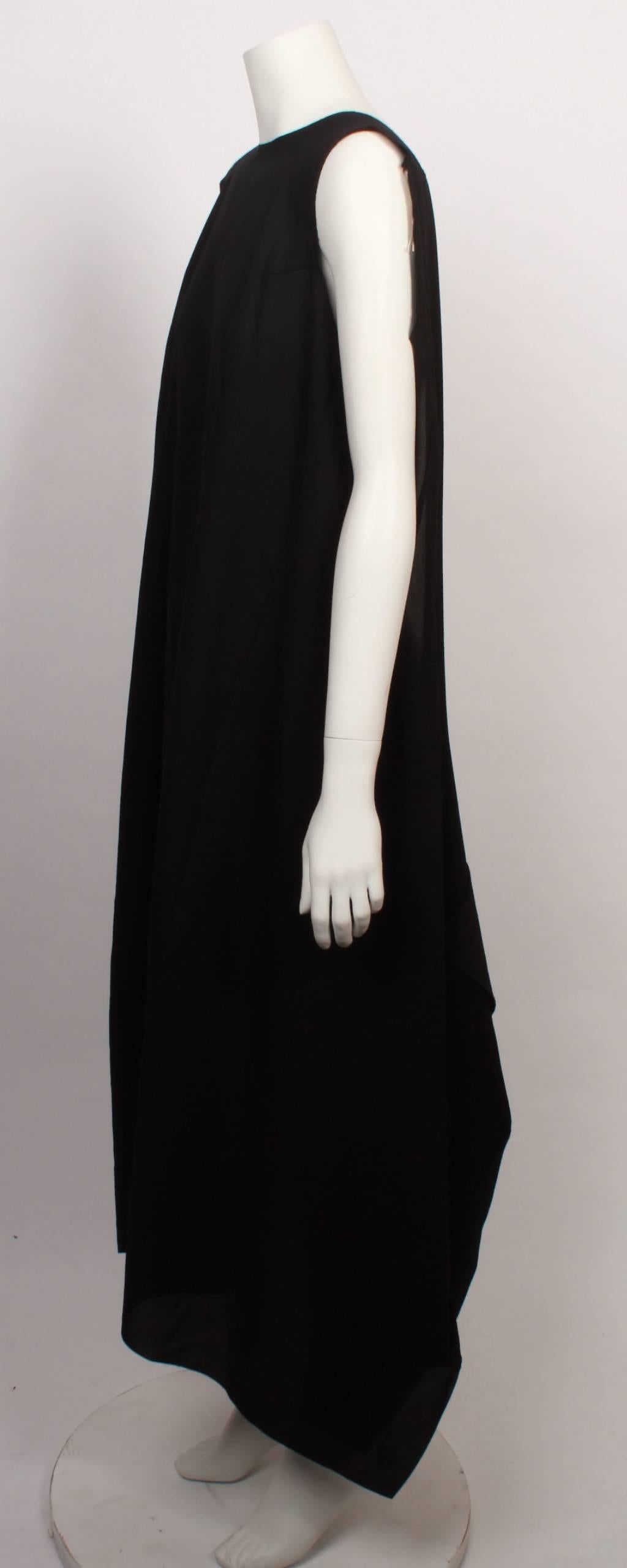 Comme des Garcons  black layer dress with long scooped out section that can be converted and reversed to be worn a myriad of ways. 
Fabric is a textured georgette and the dress is sleeveless and has raw edges. 


