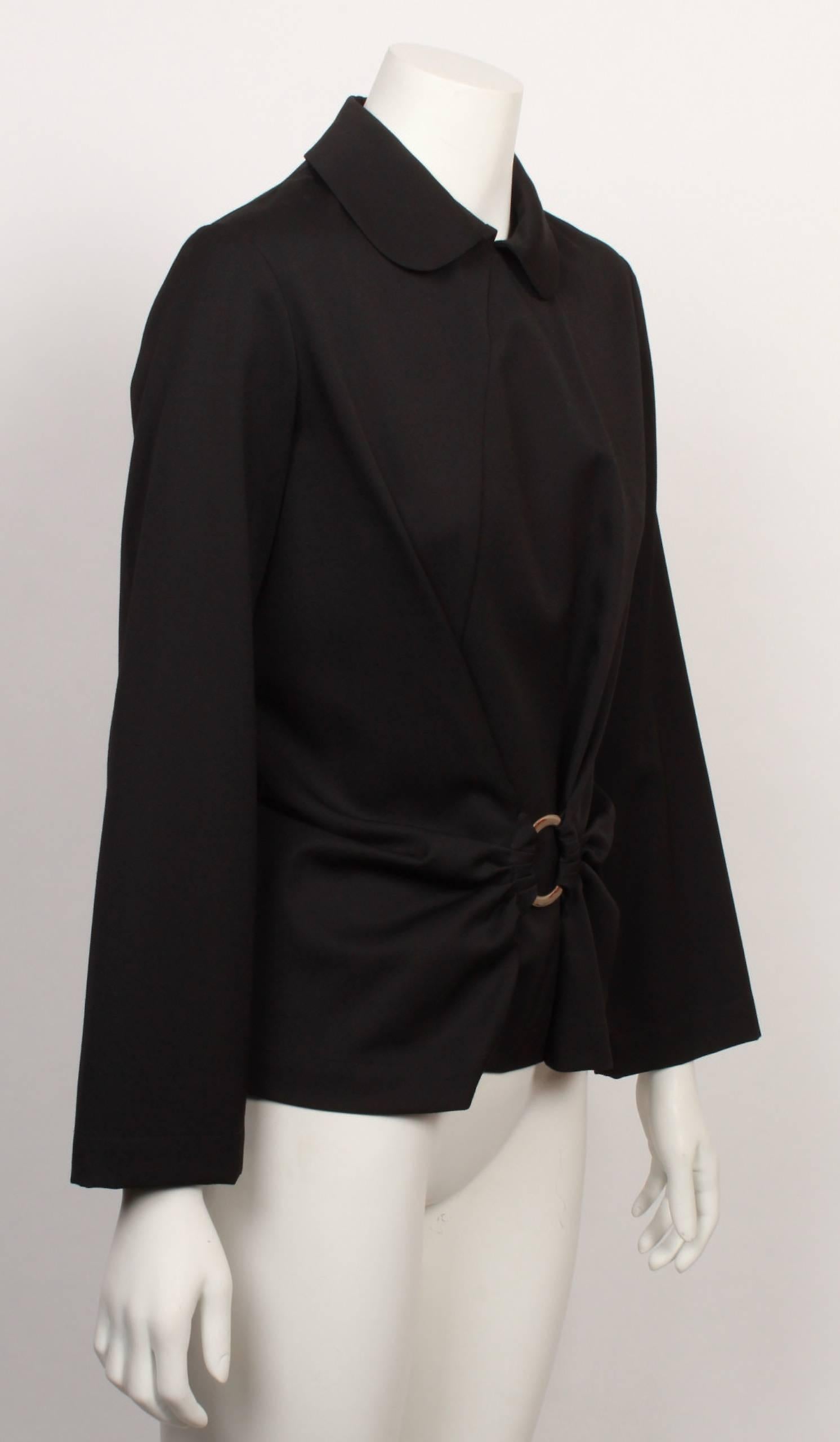 Junya Watanabe Comme Des Garcons black shell top with long sleeves, peter pan collar and curved front and back panel. Decorative nickel ring at the centre front with draped and gathered feature create a flattering silhouette by nipping in the waist.