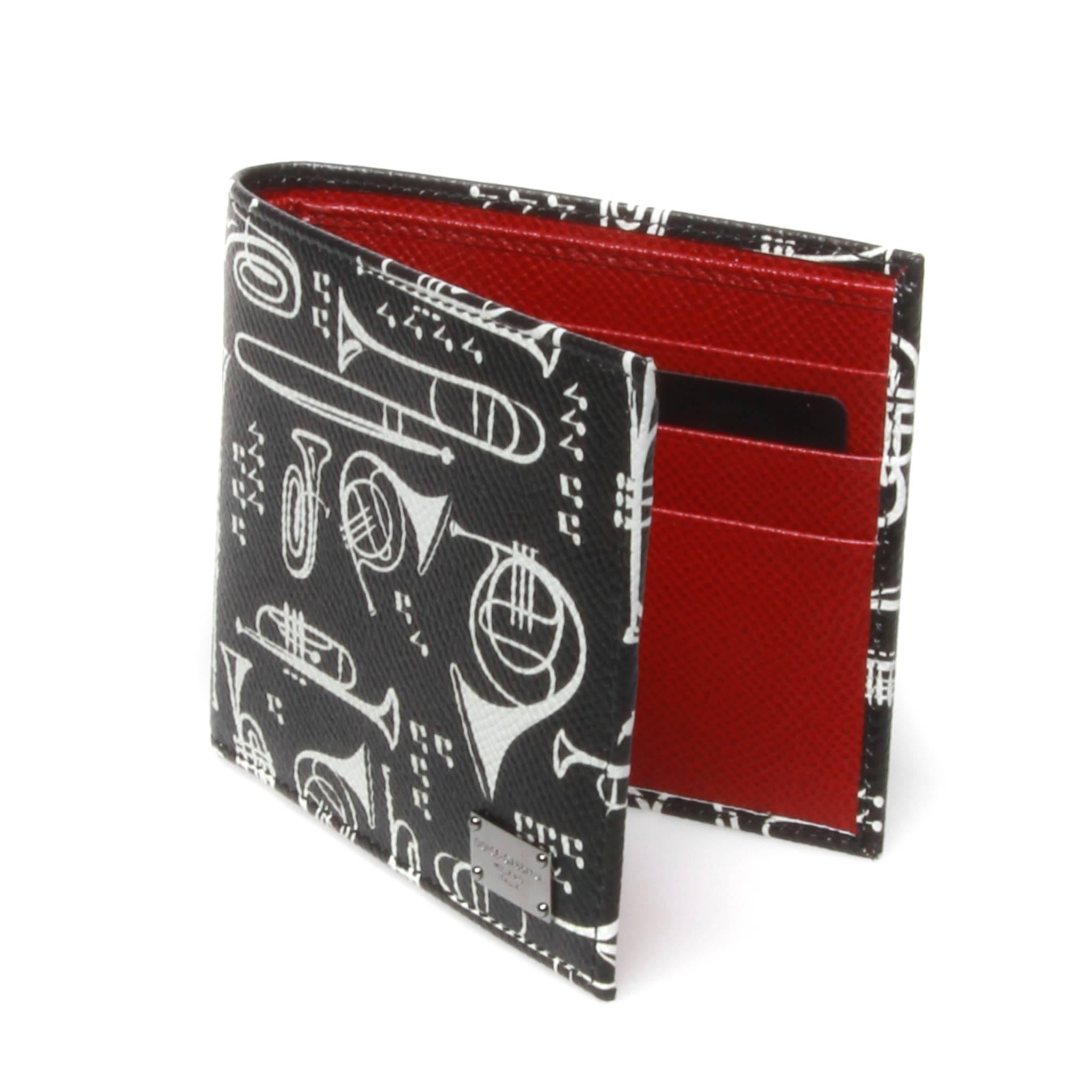 FINAL SALE

Dolce and Gabbana bi-fold dauphine calf leather wallet featuring a contrasting white musical instrument themed graphic. Red interior features 6 card slots and sleeve for notes and receipts. Silver-tone metal brand plaque to front side. 