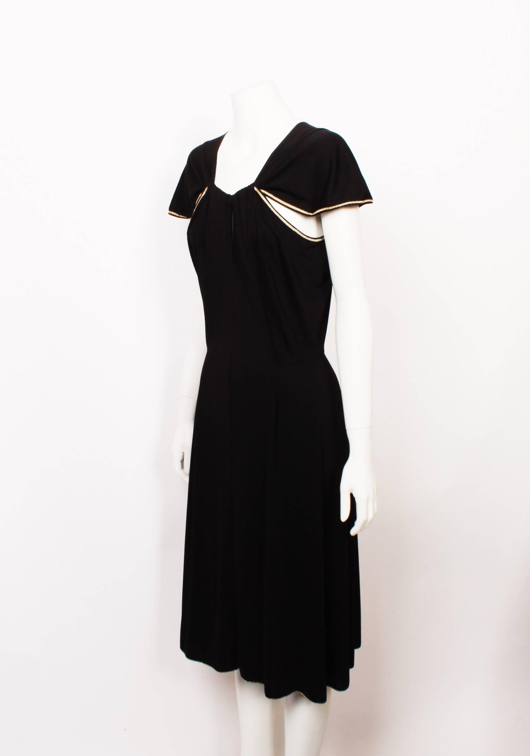 Yves Saint Laurent black fine knit jersey dress with golden satin stitch trim on all edges. From the Spring/ Summer 2011 Colection. Fitted bodice with three peek-a-boo openings and a delicate flounce petal sleeve. Flattering flared skirt silhouette.