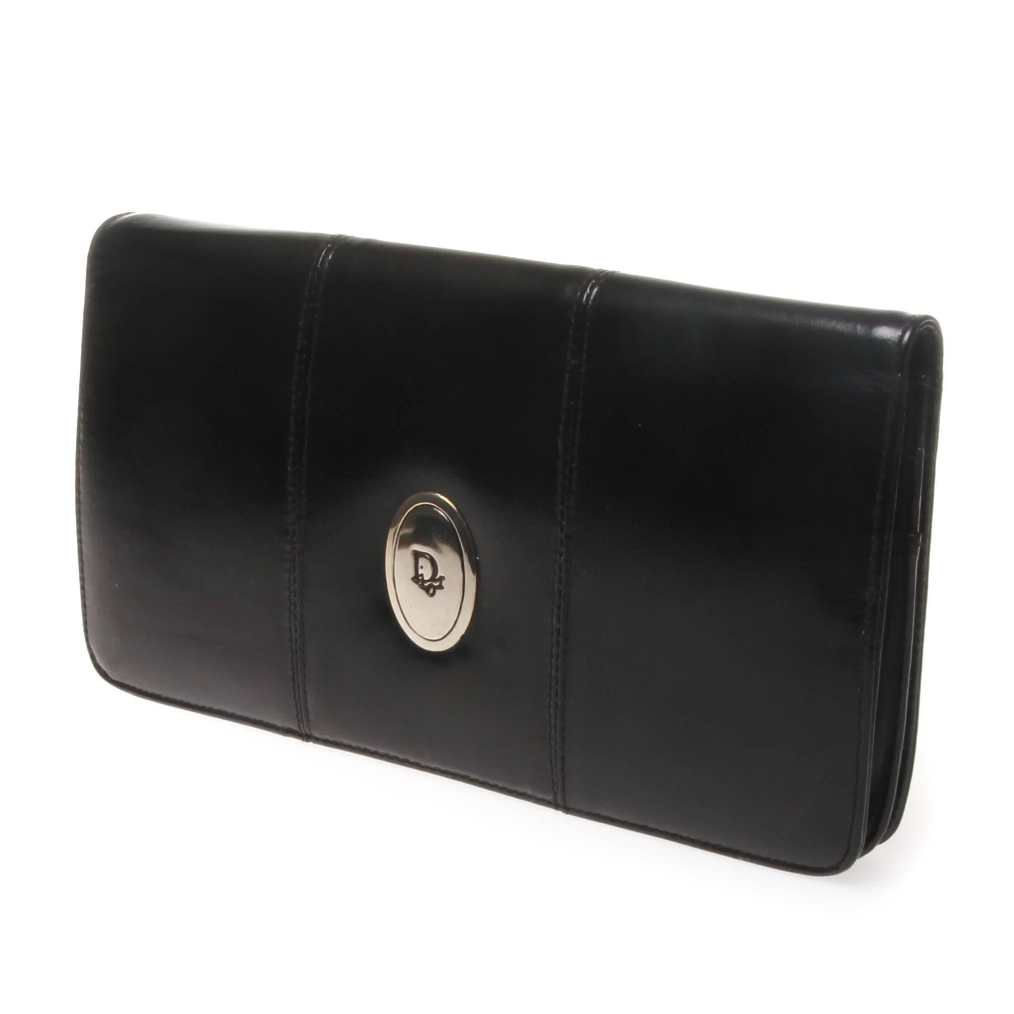 Christian Dior black leather clutch walter with 'Dior' plaque in silver on the front. Inside there is one main pocket with two sewn in pockets, one with a zip. There are also two other compartments one fastened with a clip for coins and one with a