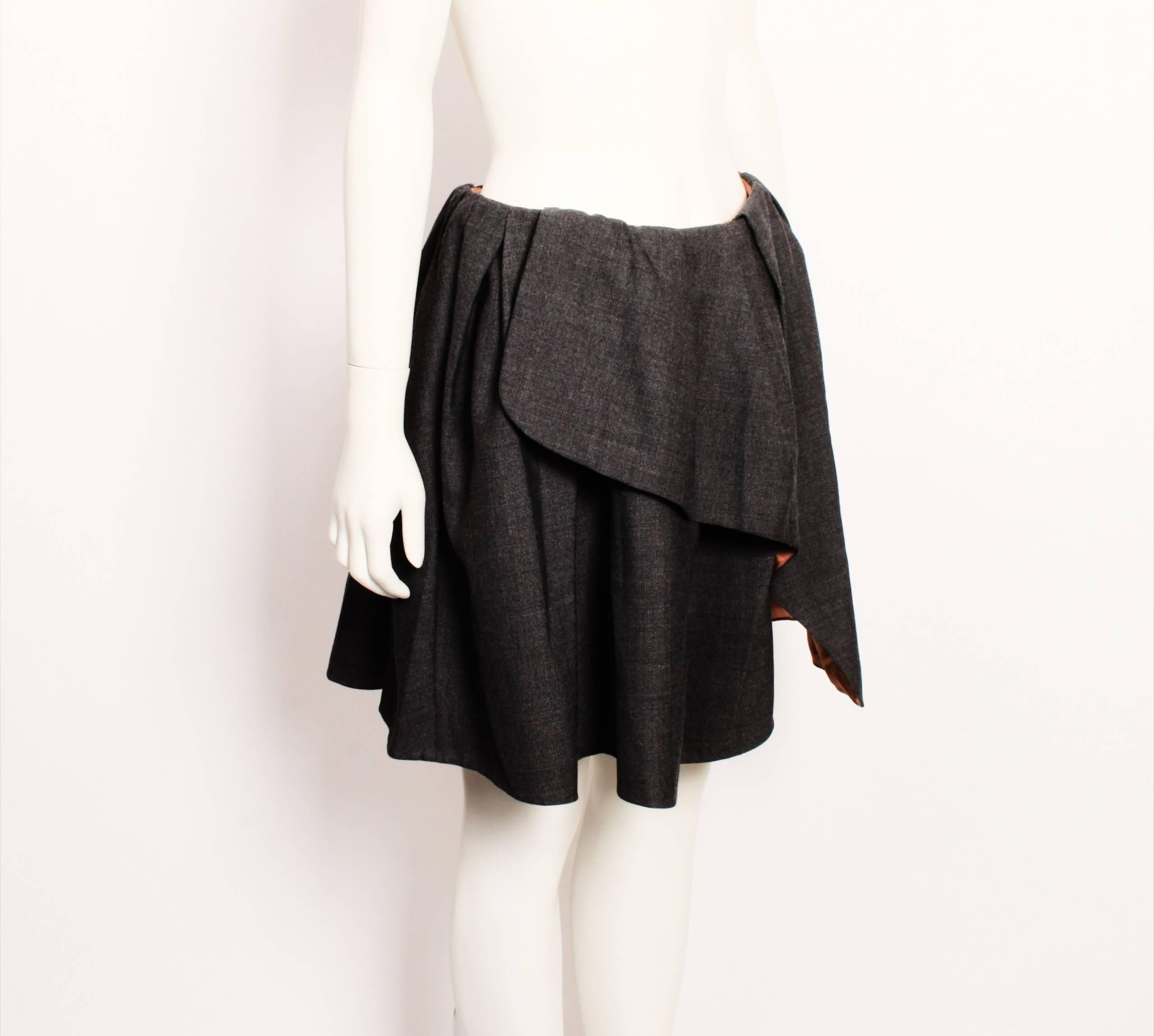 Cute Carven mini skirt in grey wool blend . Features wrap in petal shape panel, pleats, back invisible zipper and lovely toffee coloured lining and grosgrain ribbon waistband. 

