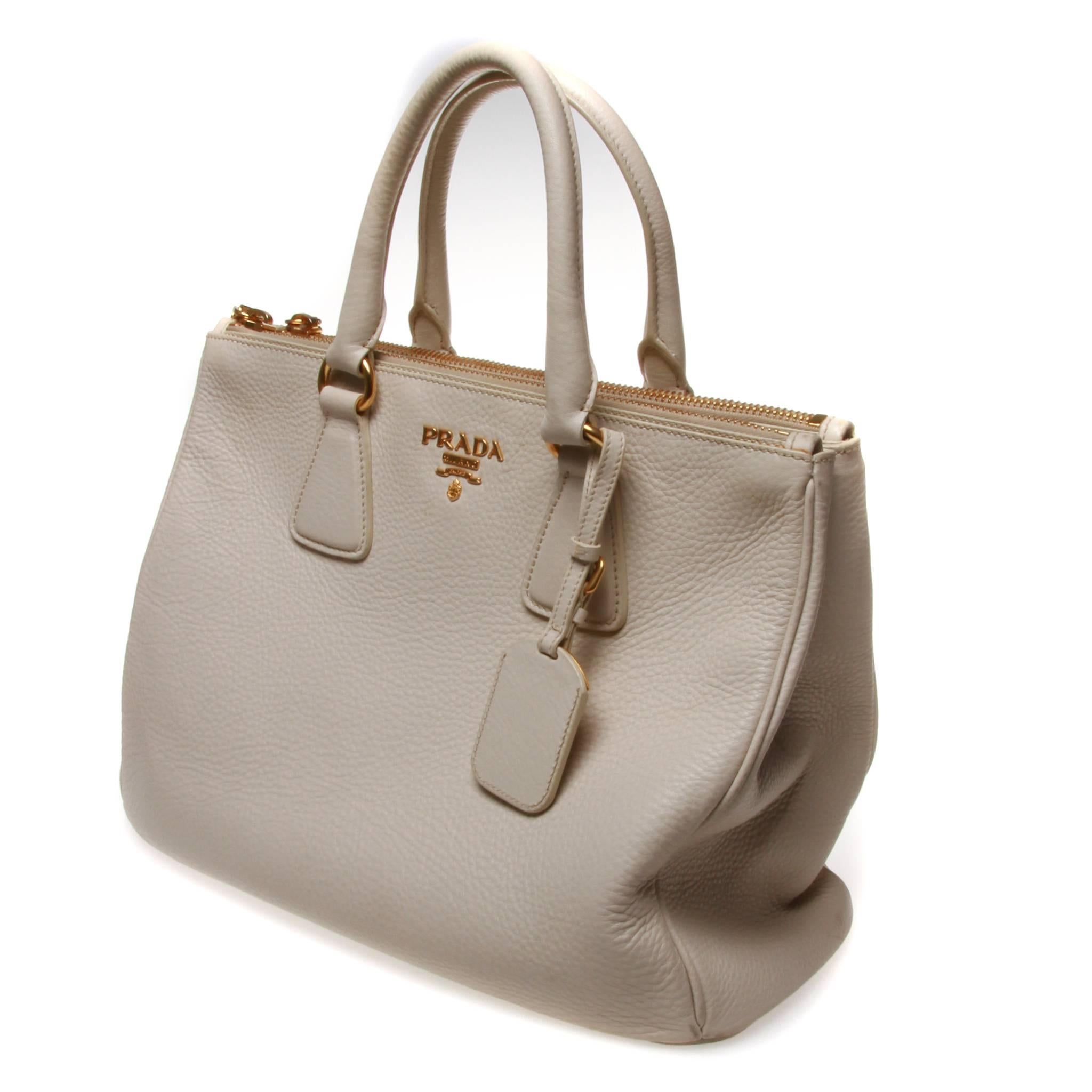 Cream grained leather Prada Double-Zip tote with gold-tone hardware, dual rolled top handles, logo placard at front, protective feet at base, cream logo jacquard lining, three interior compartments; two with zip closures, four pockets at interior