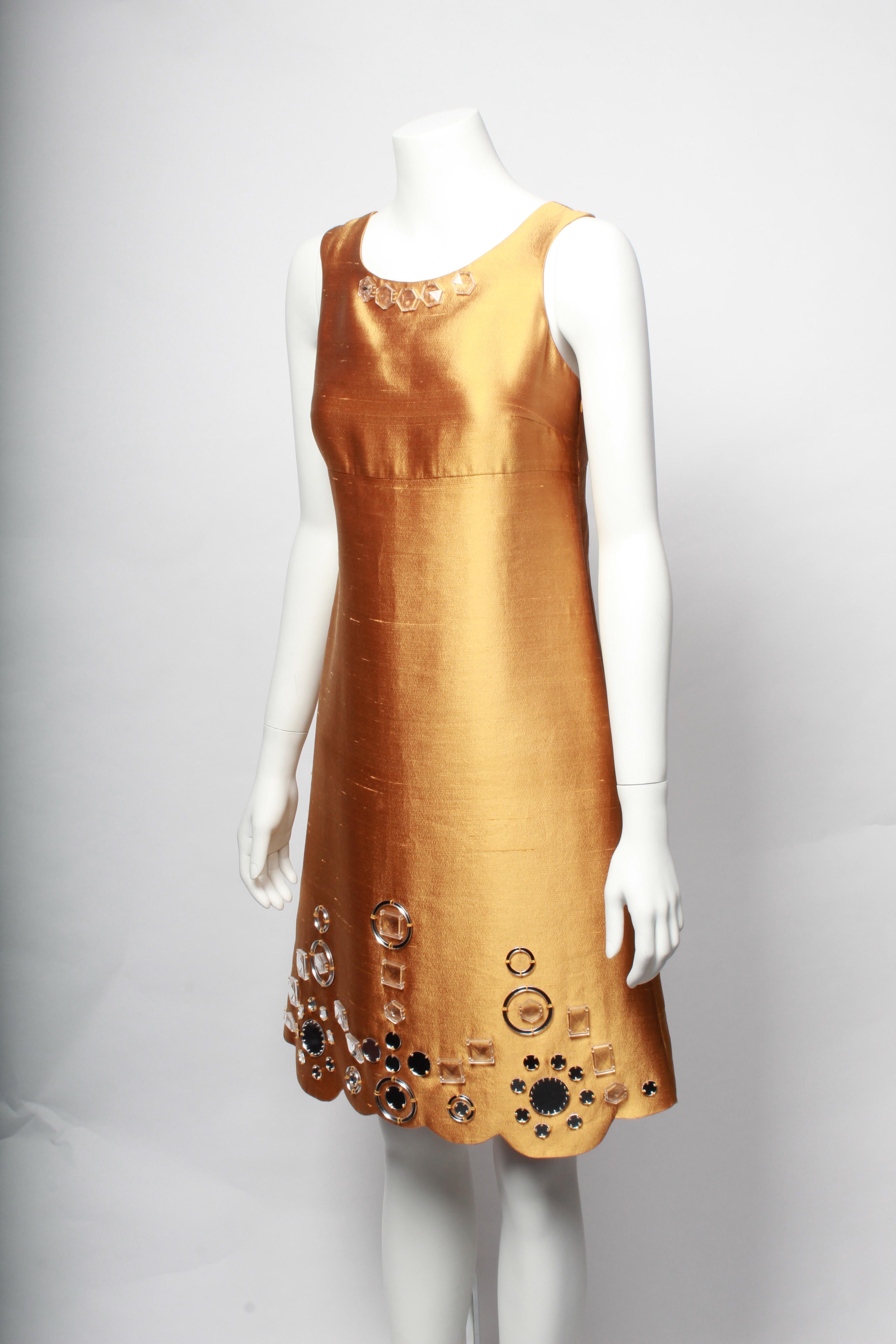Gorgeous Miu Miu Gold Shift Dress. The dress is cut in a flattering A-line shape from under the breast.
Made in wonderful gold silk, this dress features patterned mirror embellishments and is finished with a scalloped hem.
An excellent party dress