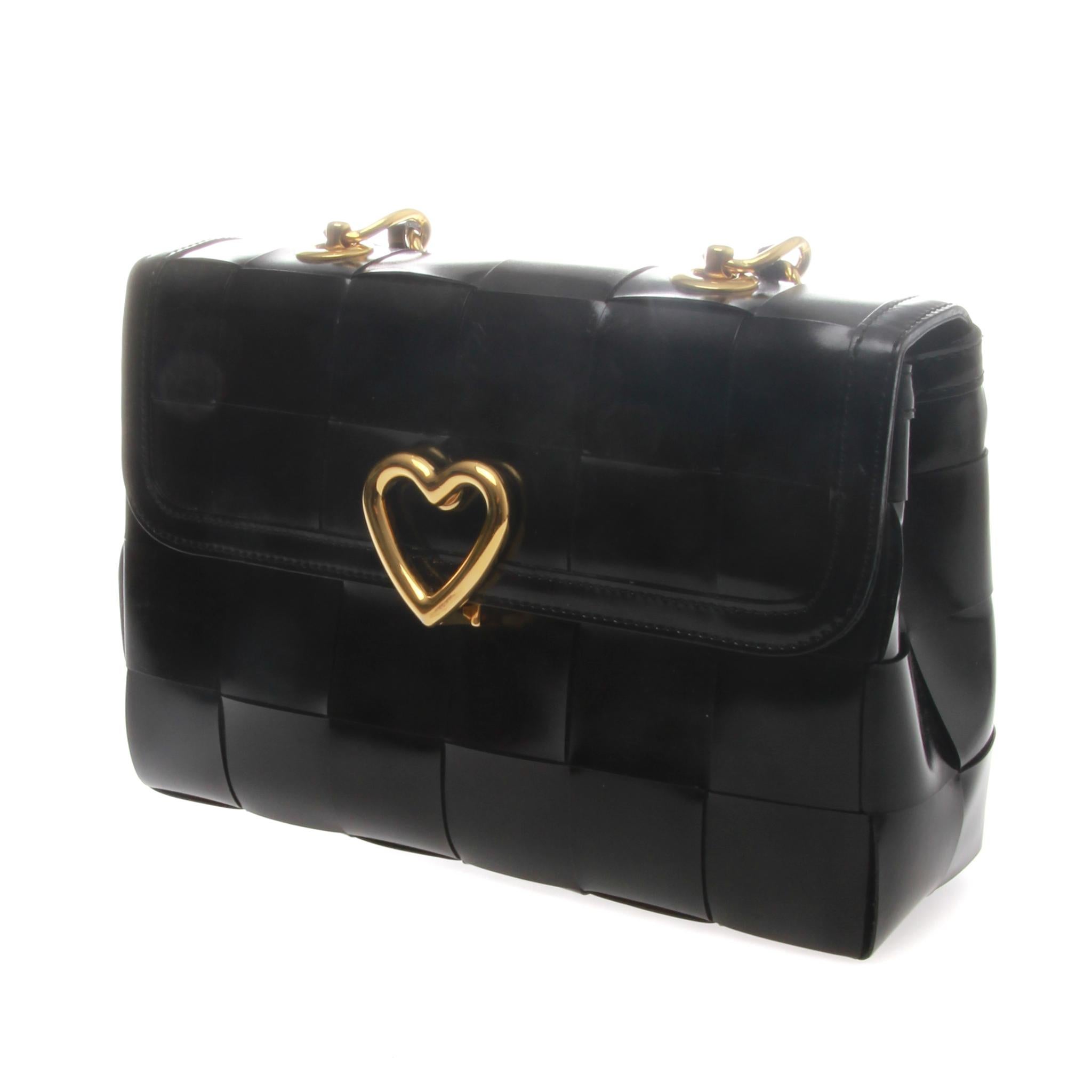 A fabulous-rare Love Moschino Intrecciato Leather Handbag.

It features a braided black leather with a large gold-tone love shaped press button closure and a gold chain trimmed leather strap.
Interior compartment lined with a fabric and a zipped