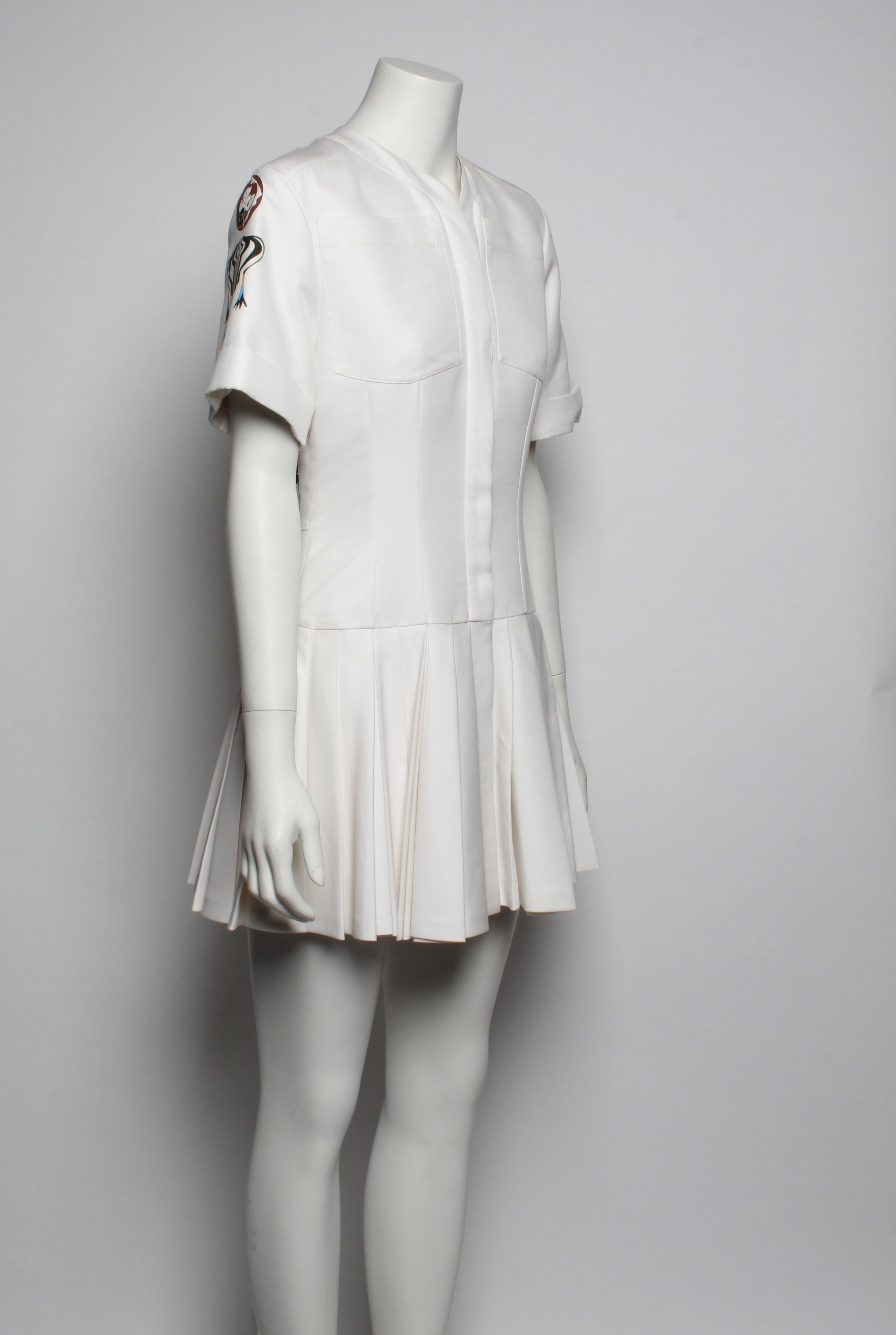 Christian Dior White Pleated Mini Dress From the 2016 Collection features a fitted shirt style bodice with curved neckline, patch breast pockets and short cuffed sleeve with abstract floral CD print. Back features a large floral print, and skirt is