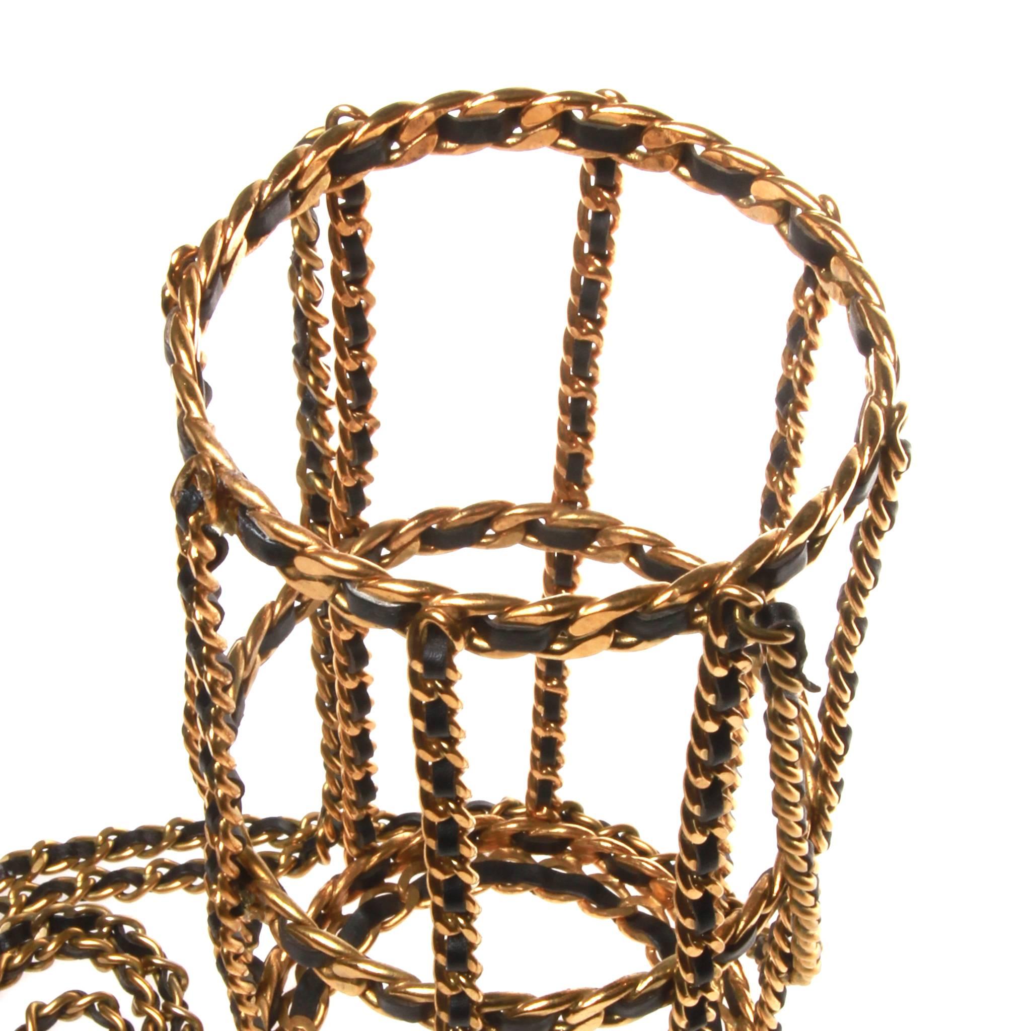 Rare and coveted Chanel Fall 1994 wine bottle holder. Formed of the classic Chanel leather threaded chain, the simple cage design in gold-tone metal and black lambskin features a single bottle holder and shoulder or cross body strap. For the show