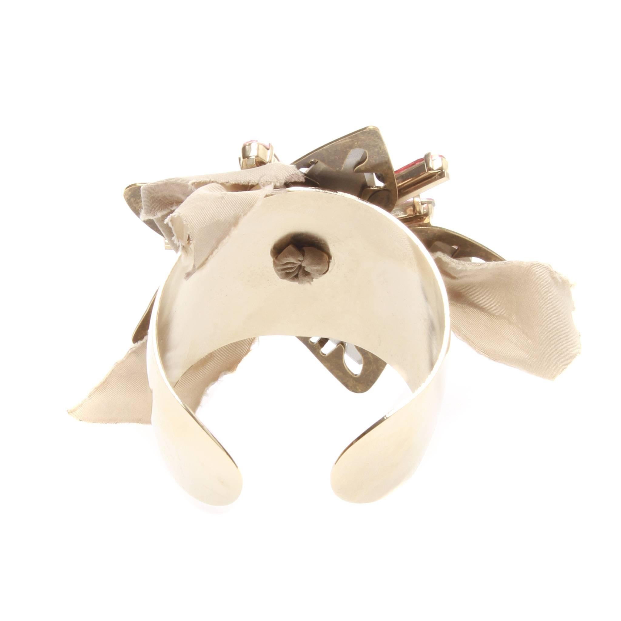 Lanvin gold-tone metal open cuff design affixed with a flower centrepiece formed of Swarovski crystals, metal and beige silk. 

Made in France. Comes with authentic box.

