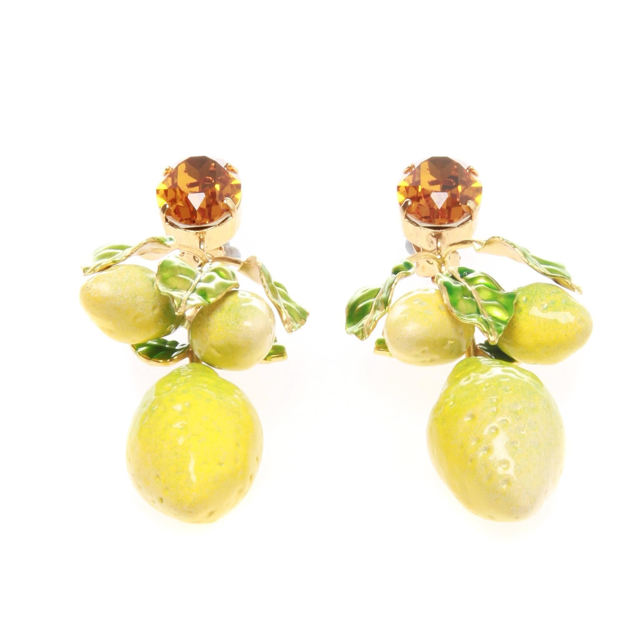 RTW Spring 2016 yellow crystal and gold-finish brass lemon drop clip-on earrings from Dolce & Gabbana featuring an amber Swarovski crystal and hanging green resin leaves with bright yellow enamel fruits. These earrings come as a pair and exude